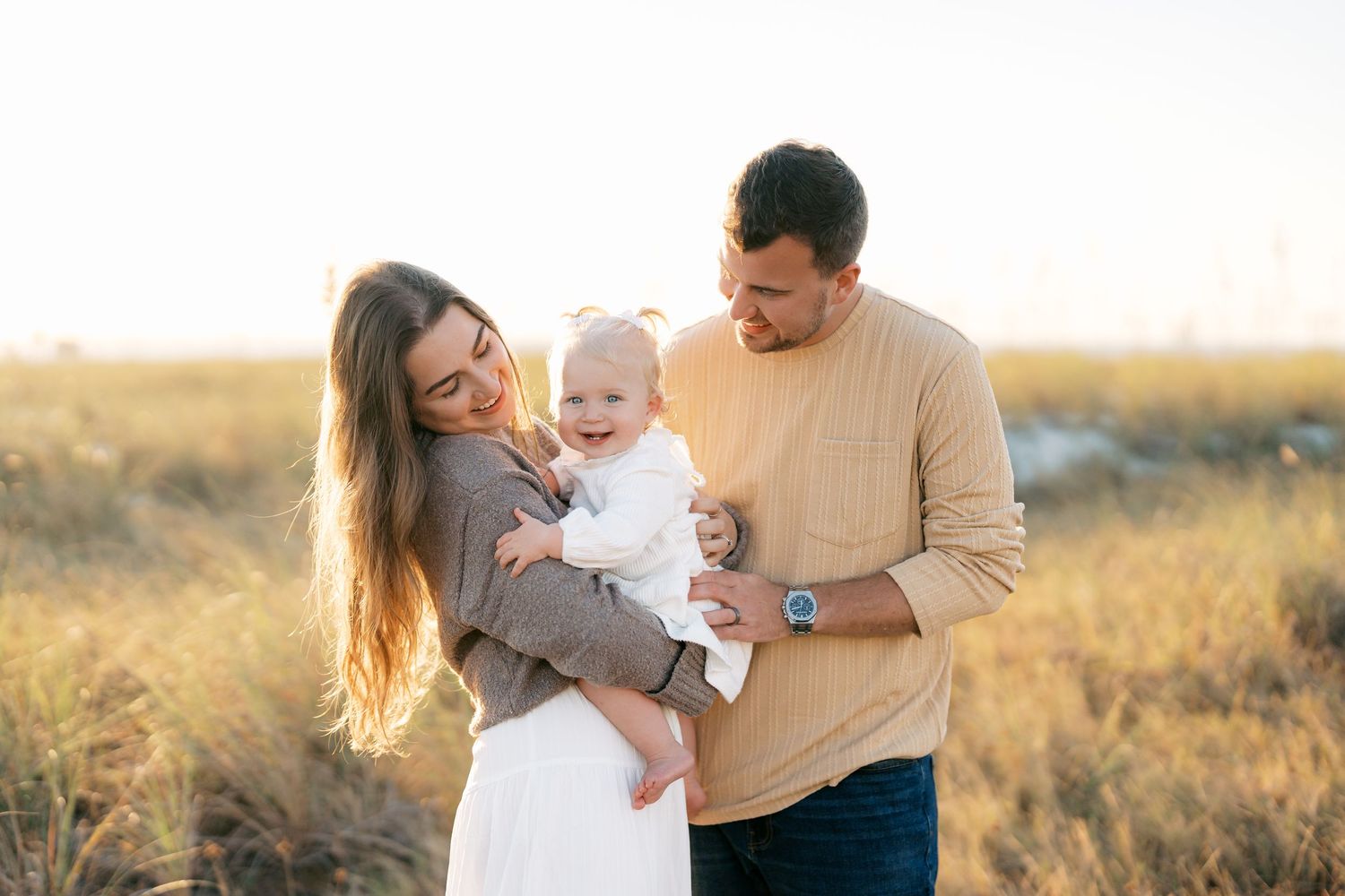 A family shares joyful moments together in a golden field during sunset.