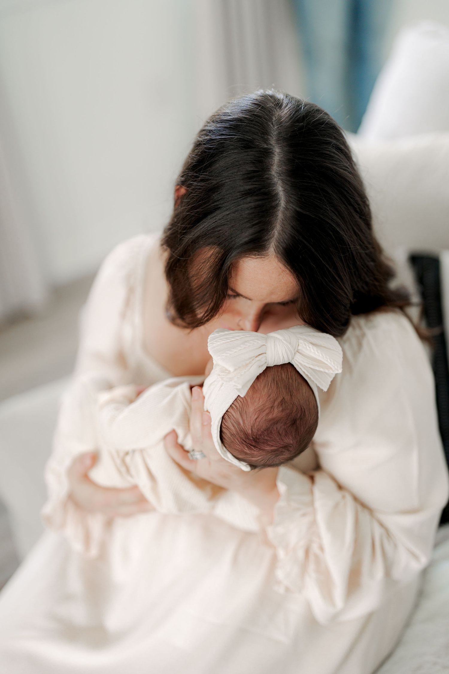 Close-up details of baby wearing cream colored bow outfit against white background.