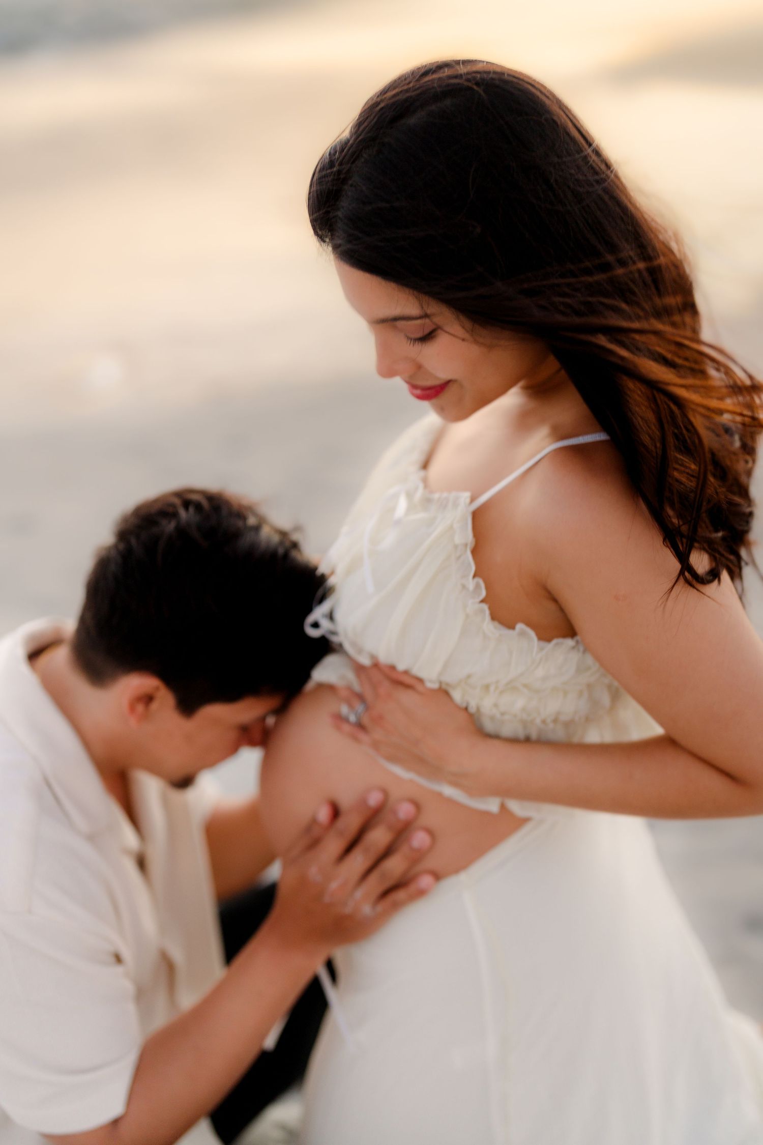 A tender maternity photoshoot series showing a couple in white sharing intimate moments at sunset.