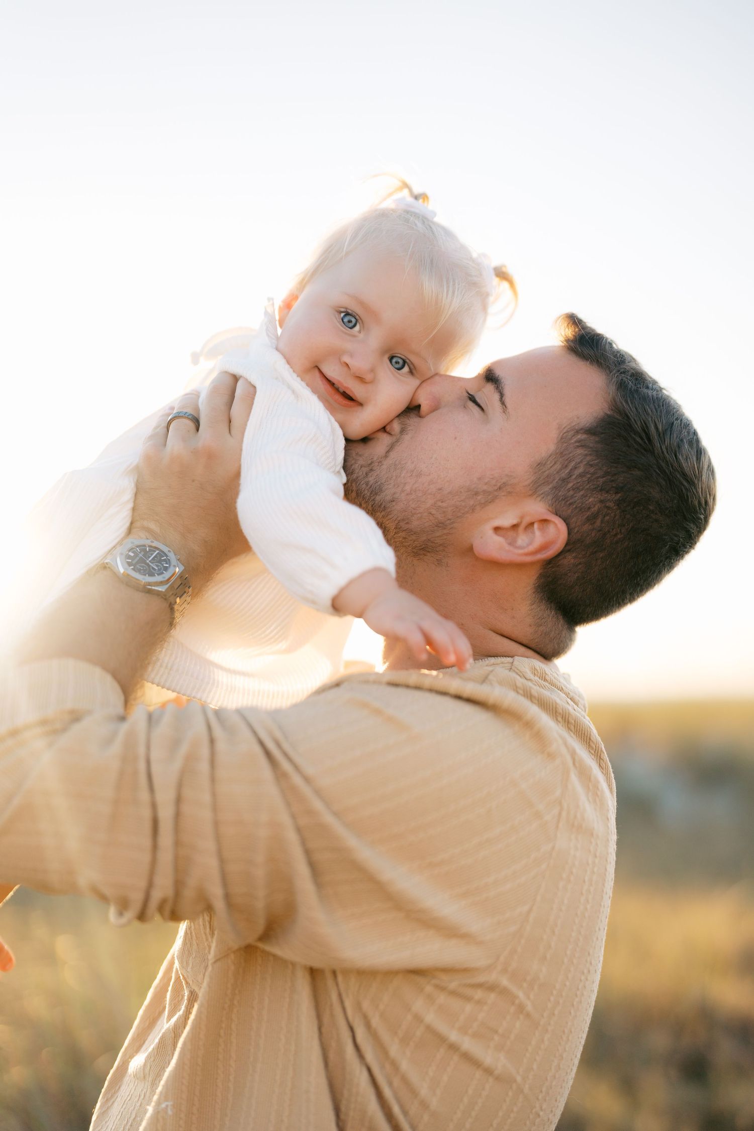 A tender moment between parent and child during golden hour in a natural outdoor setting.