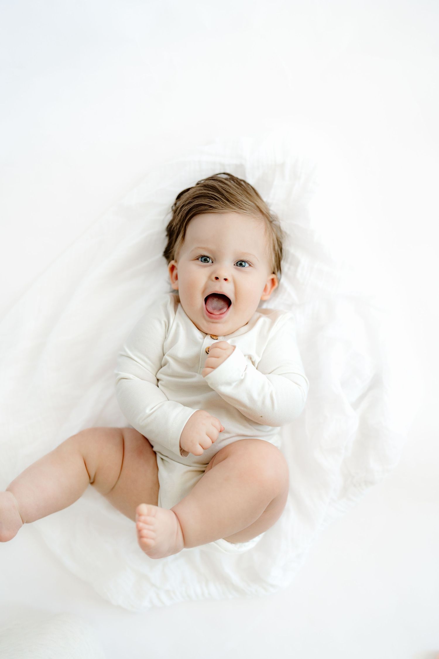 Three sweet photos of a baby in white clothing lying on white bedding showing joyful expressions and playful poses.