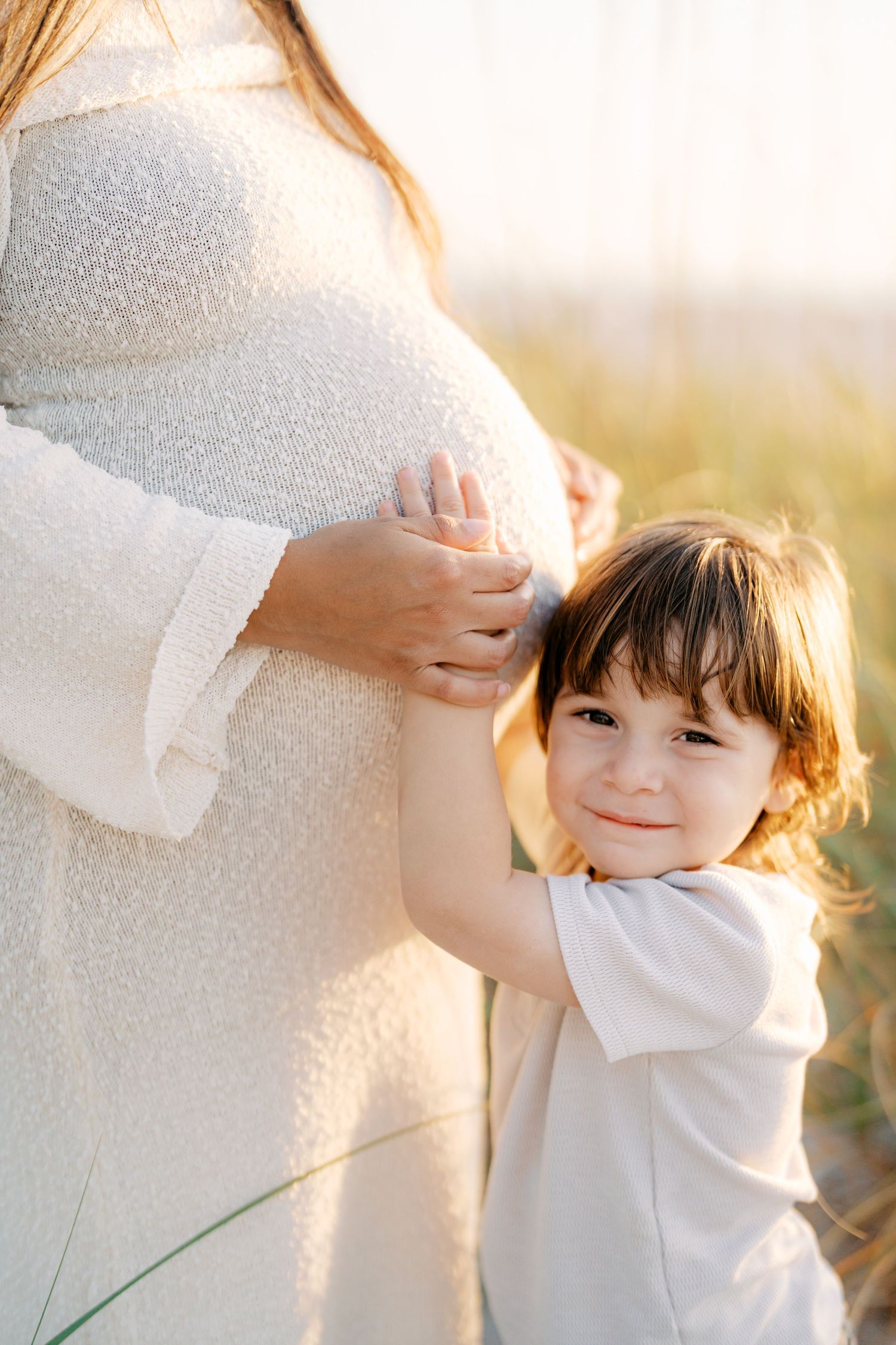 A child in a white sweater hugs someone wearing white in a series of sunlit photos showing gentle affection.