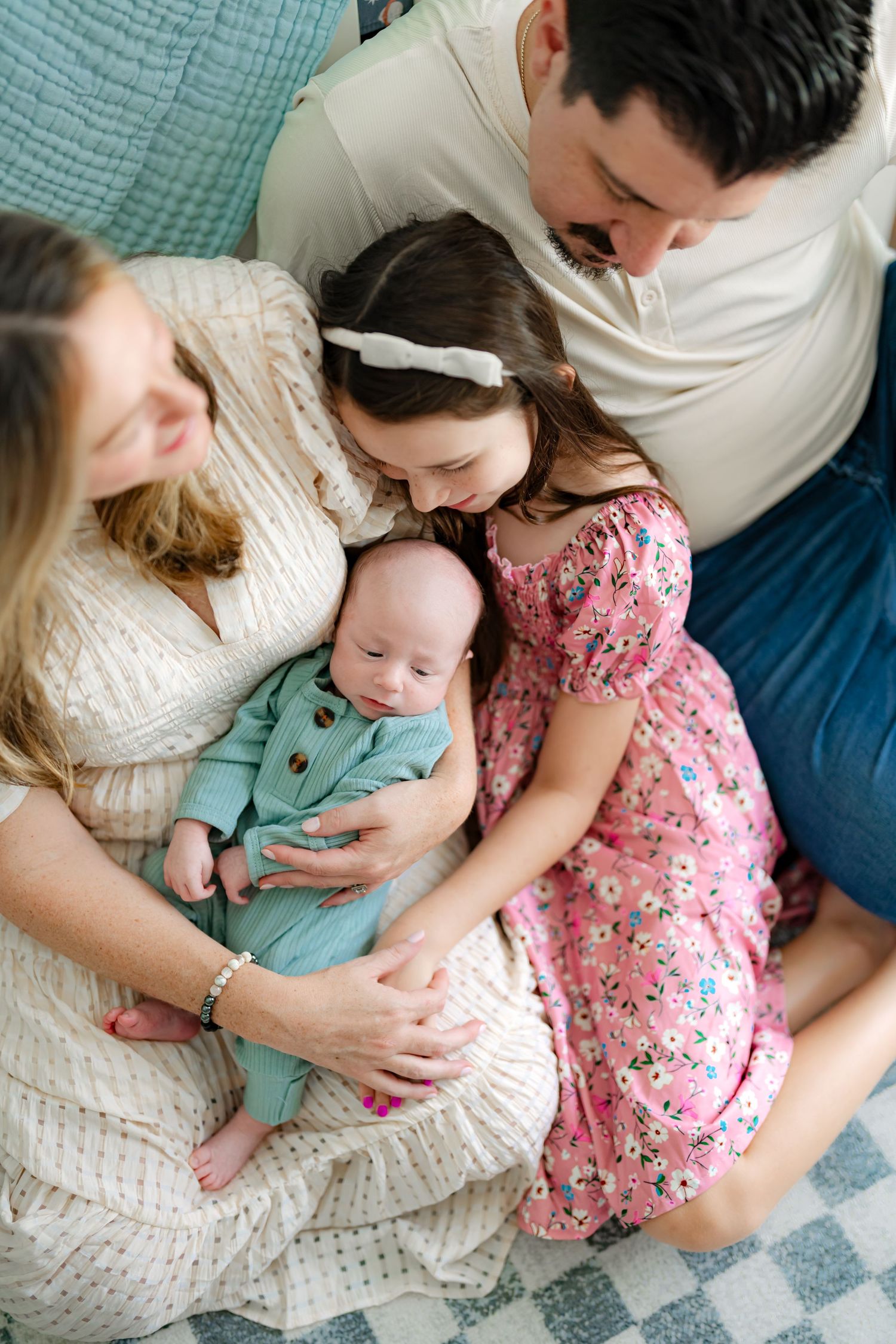 Family relaxing together on blue couch, wearing white and floral outfits in series of candid photos.