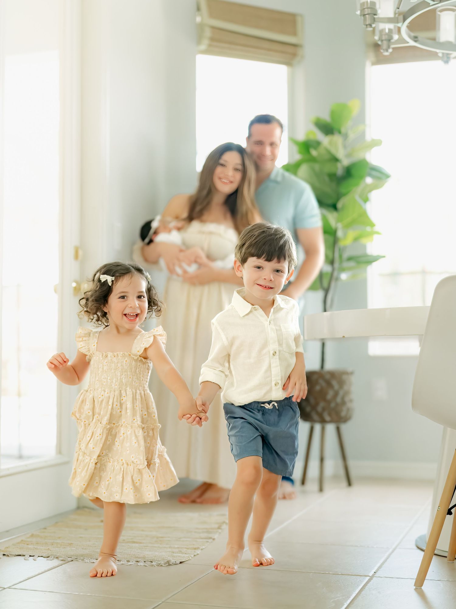 Children playing and running in bright indoor studio with parents in background.