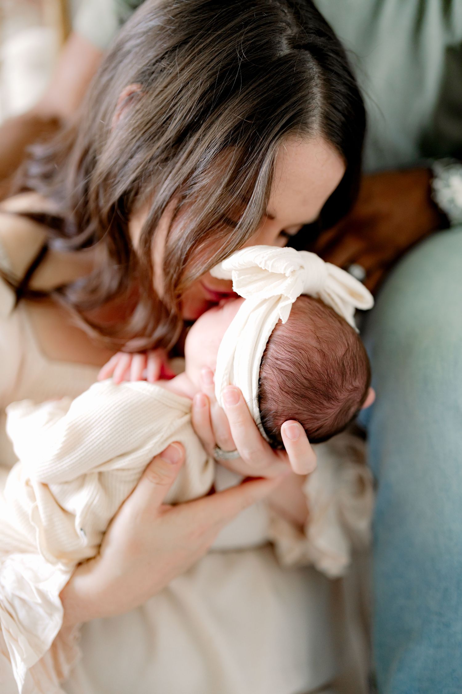 Close-up shot of baby being cradled in cream colored outfit during photo session.