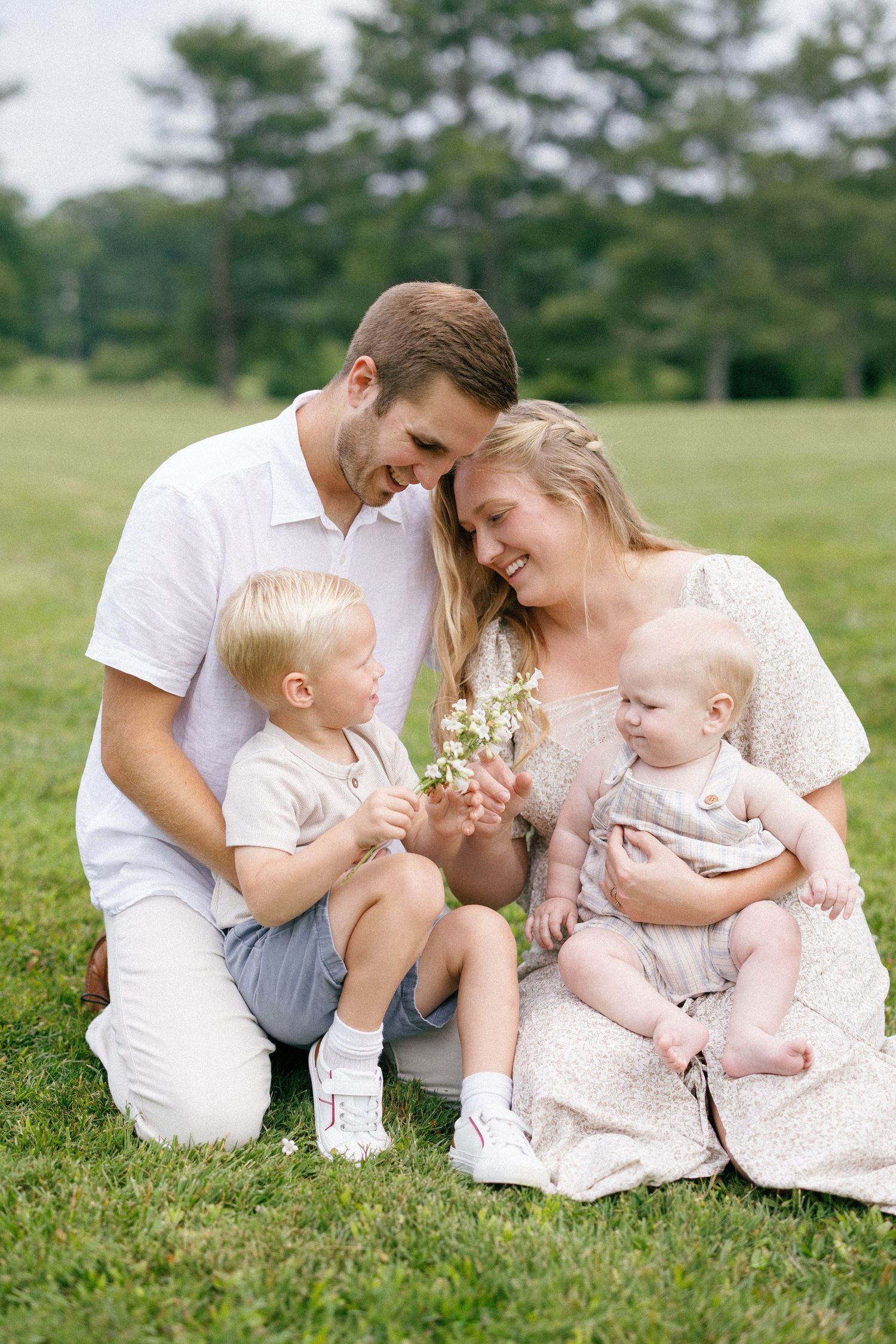 Outdoor family portrait on grass with coordinated white and cream outfits.