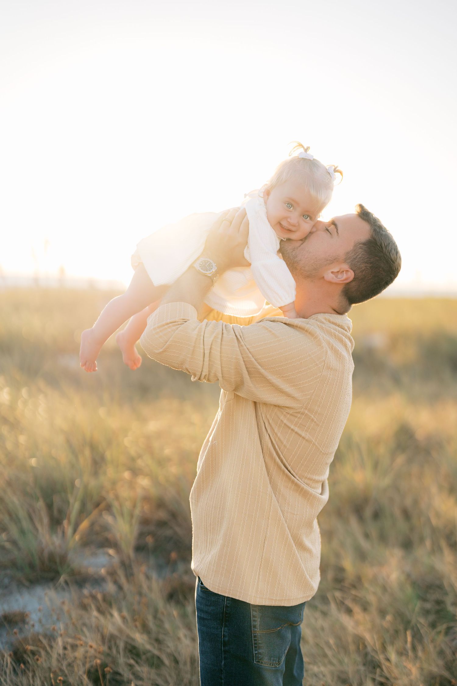 A series of heartwarming moments captured during a sunset photoshoot in a grassy field.