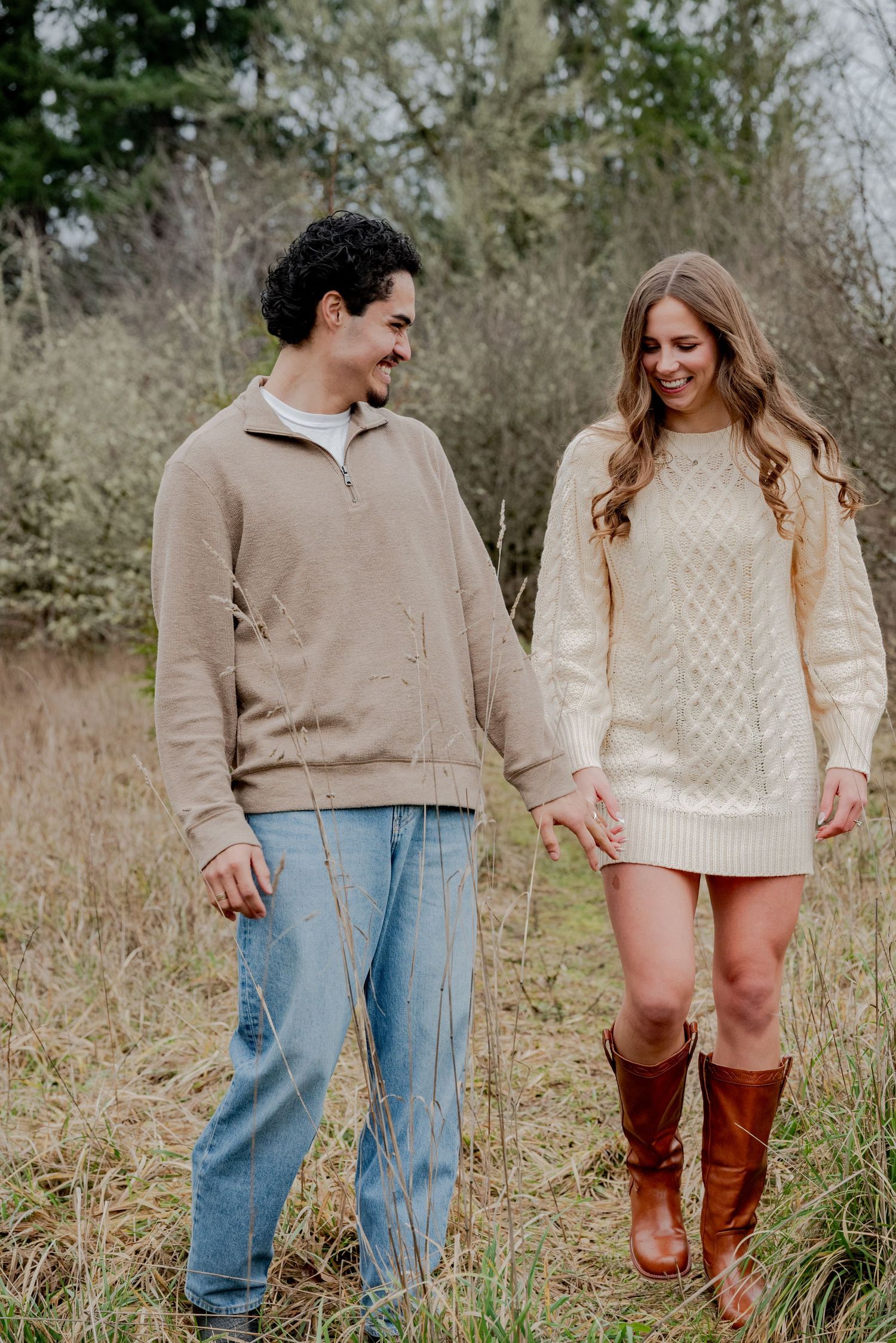 Olympia, Washington, A couple in casual fall attire holding hands and smiling while standing in a field with tall grass.