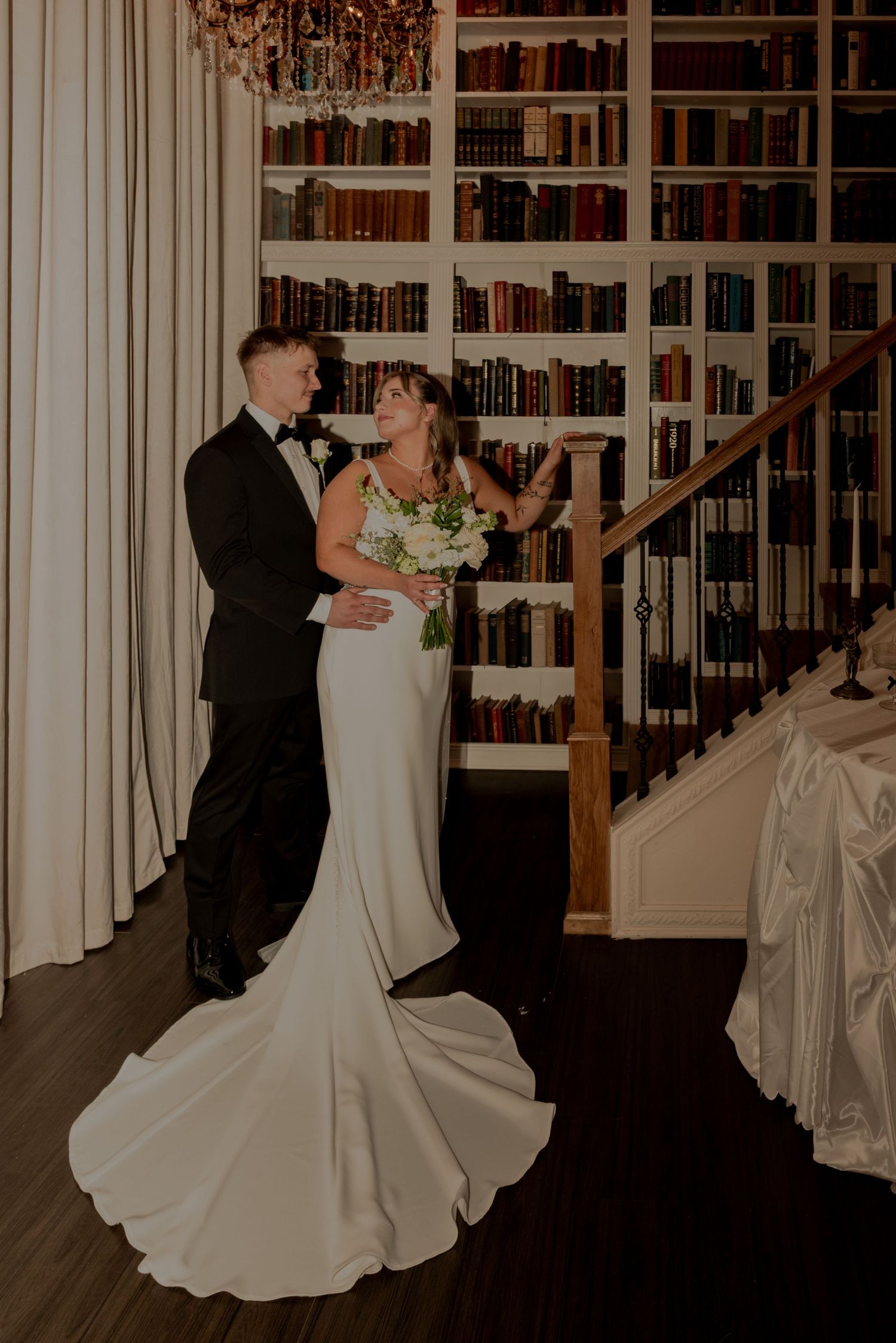 Tacmoa, Washington, A romantic wedding couple shares their first dance in an elegant library setting with floor-to-ceiling bookshelves.