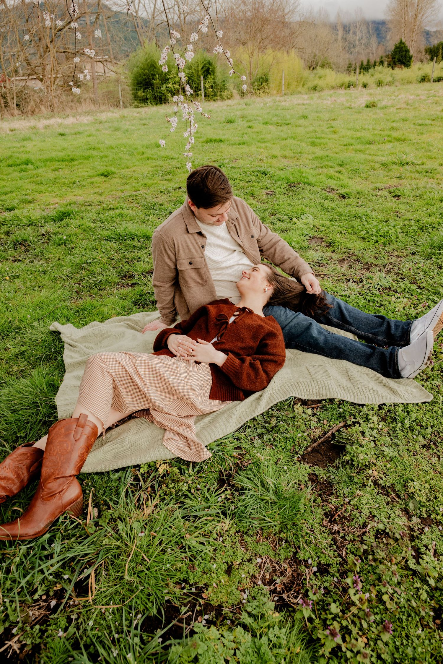 Deming, Washington, A couple relaxes on a blanket in a grassy field on an autumn day wearing cozy sweaters and boots.