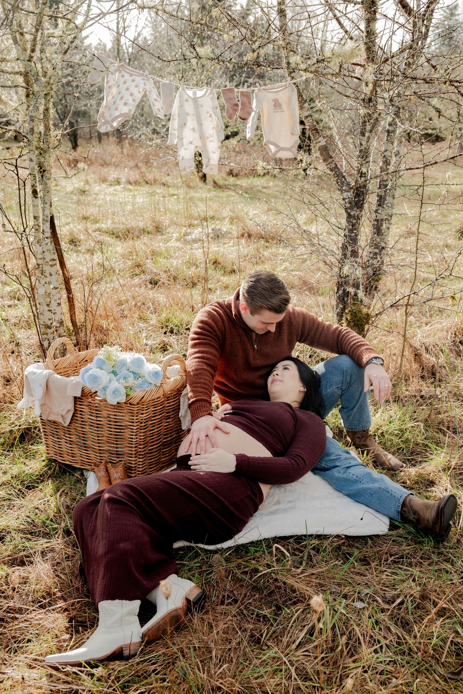 Olympia, Washington, A couple enjoys a romantic autumn picnic on a blanket in the woods with a wicker basket nearby.