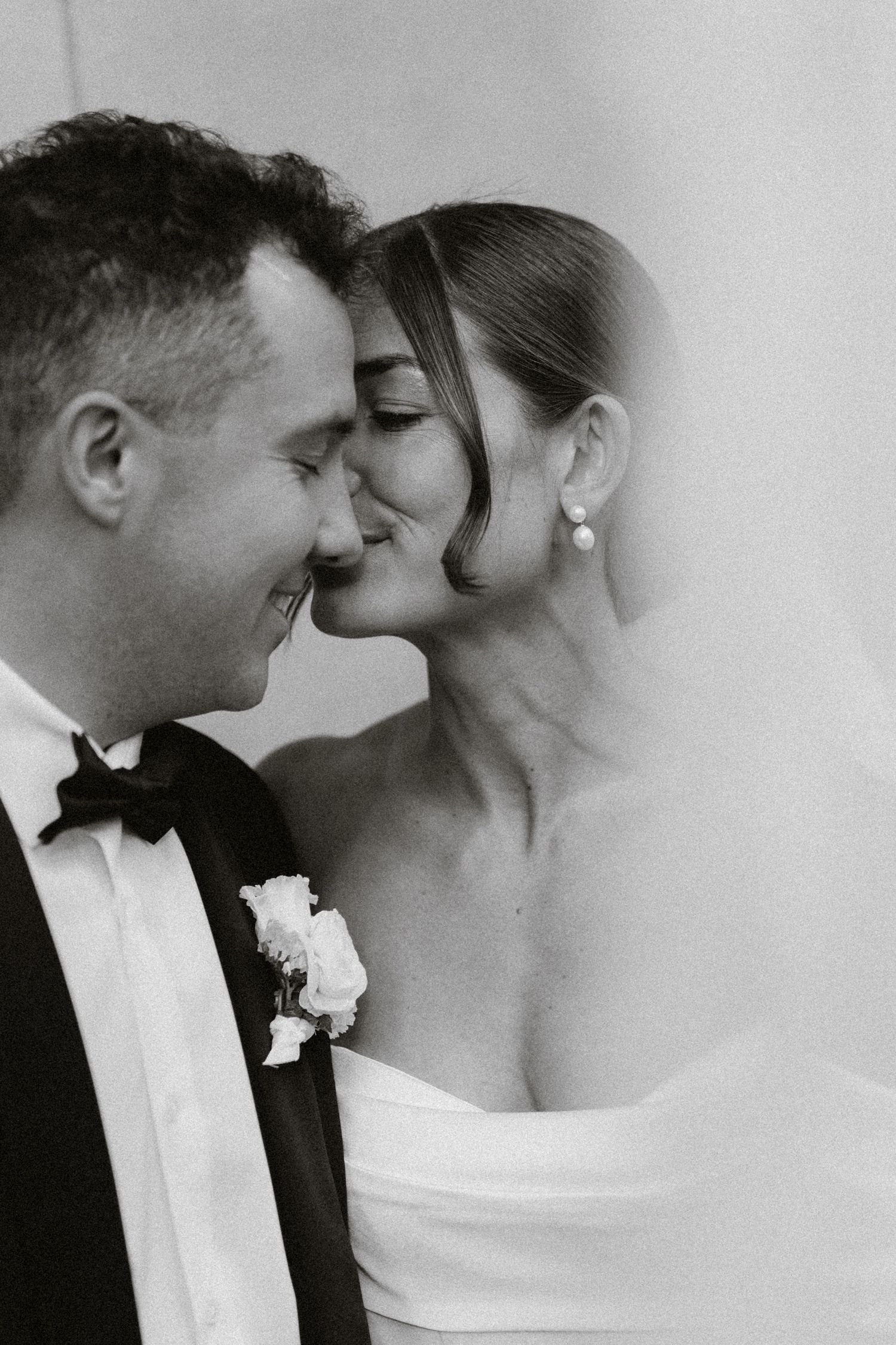 Bride and groom touching foreheads in a close black-and-white portrait.