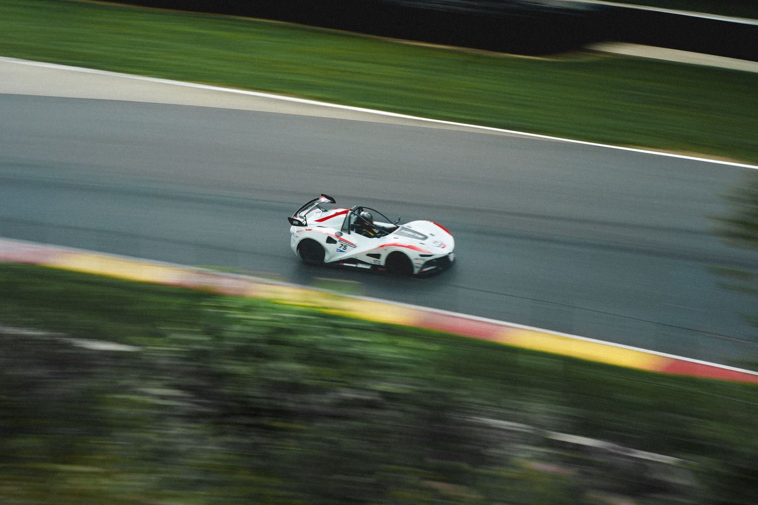 Racing car speeds around a track with motion blur effect creating a dynamic and thrilling motorsport scene.