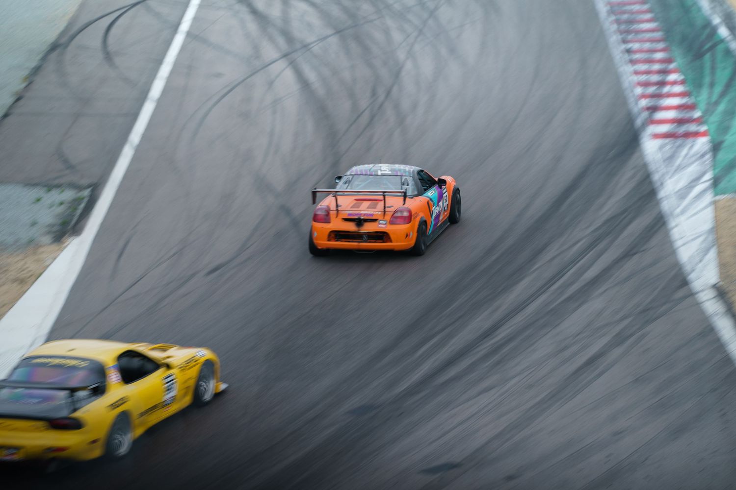Two race cars navigate a curved track with visible tire marks during drift competition.