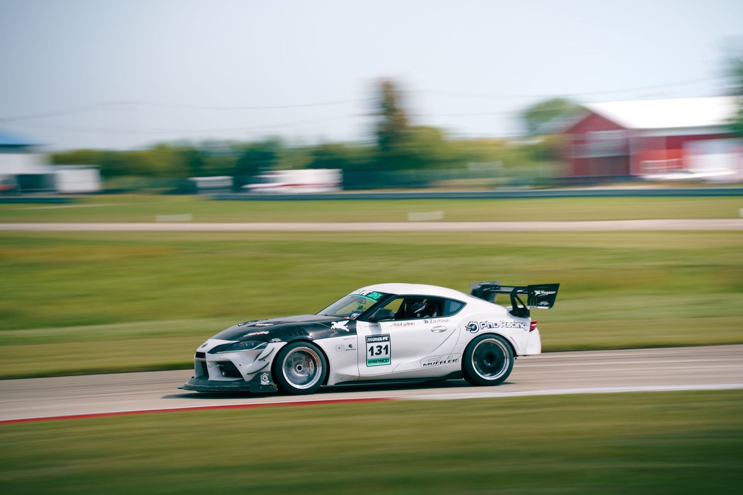 A fast-moving race car speeds down a track creating a motion blur effect during a racing competition.