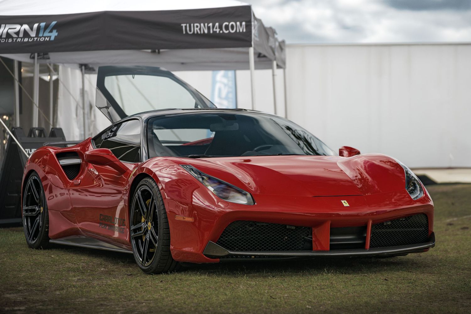 Line of red Ferrari supercars displayed under covered pavilion area.