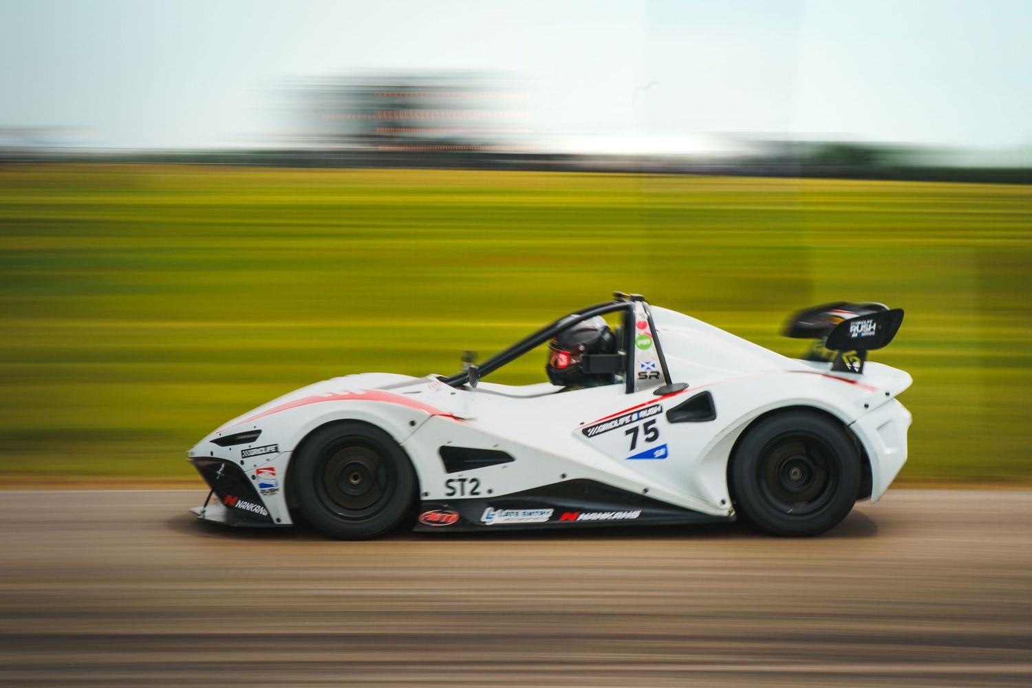 Fast racing car speeds down racetrack with motion blur effect creating a sense of velocity and energy.