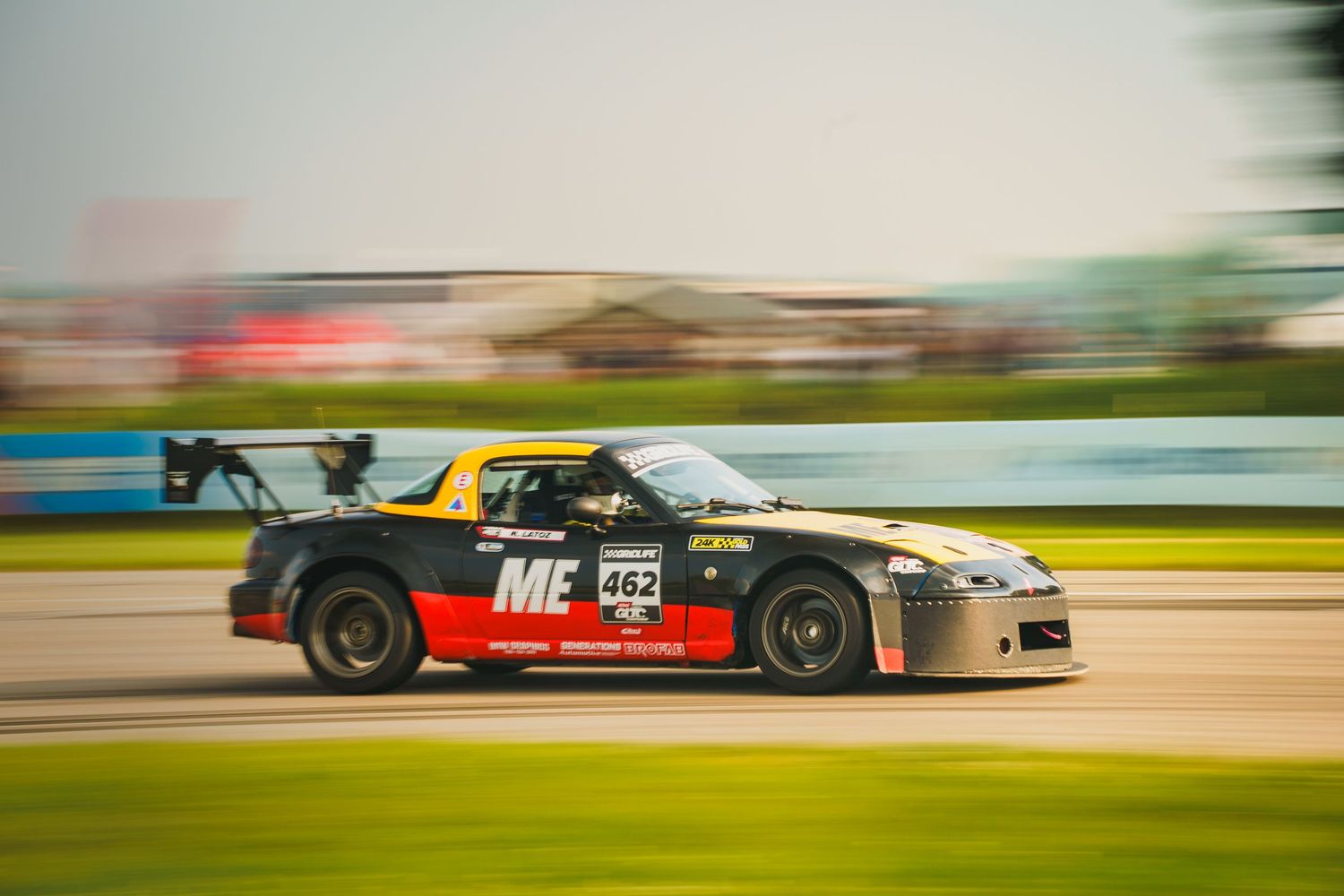 Racing cars drift around a race track corner in dramatic motion blur action shots.