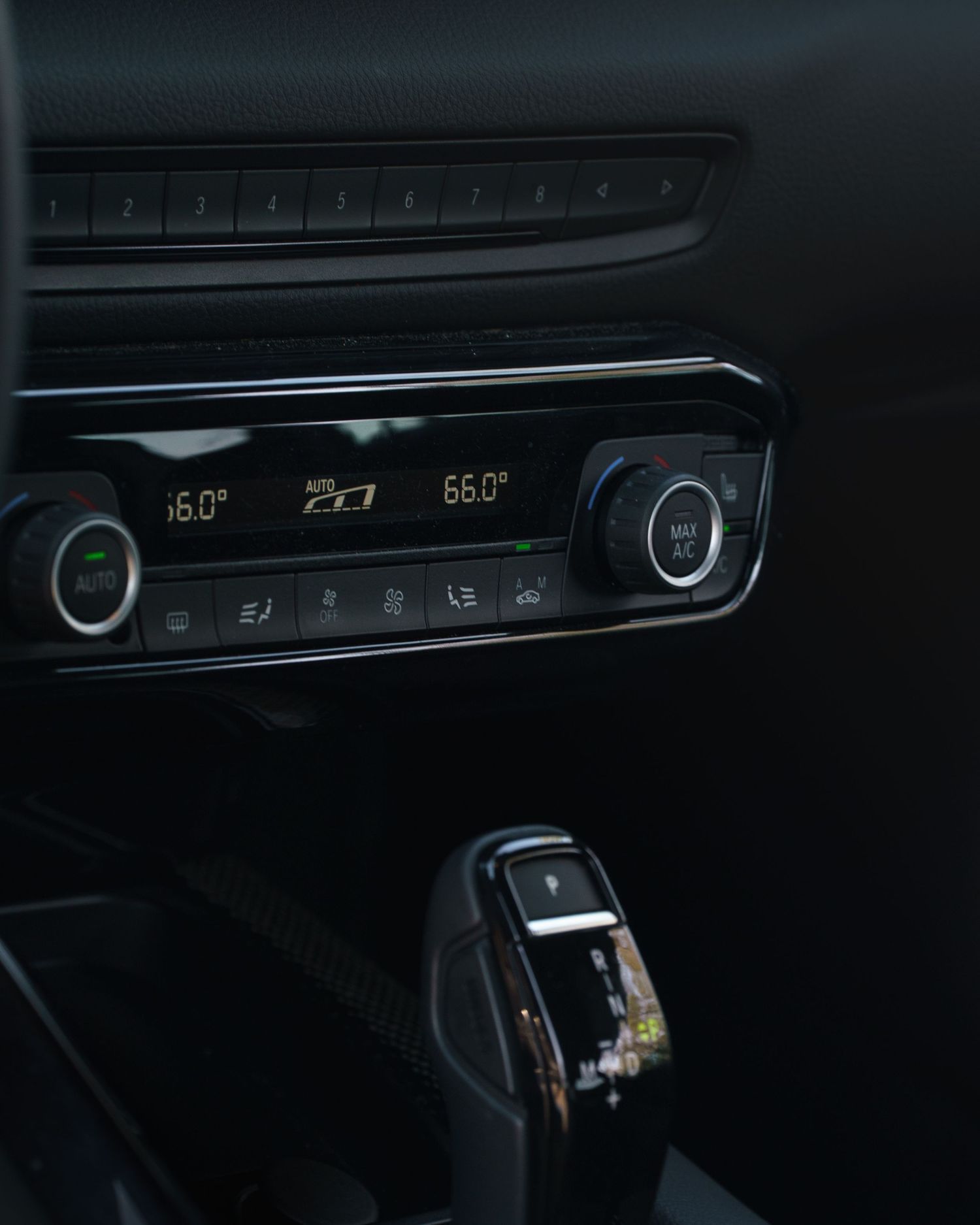 Dark interior shots of a modern car dashboard showing digital climate controls and infotainment displays.