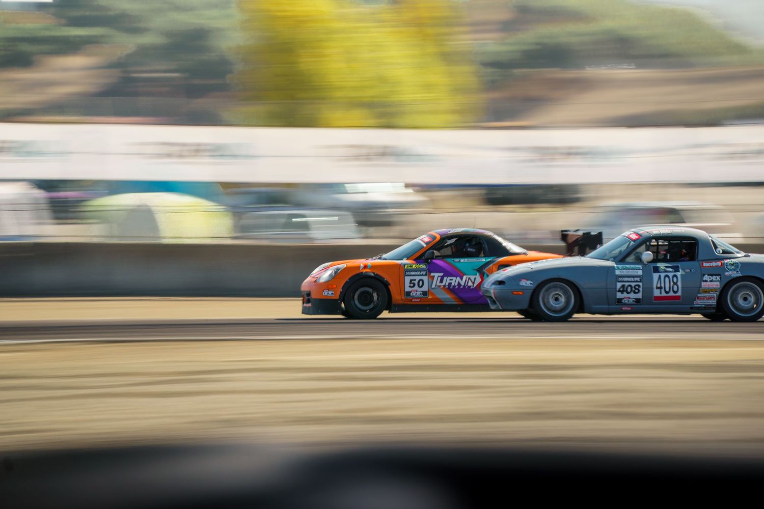 Two drift cars racing side by side on a track with motion blur effect showing high speed competition.