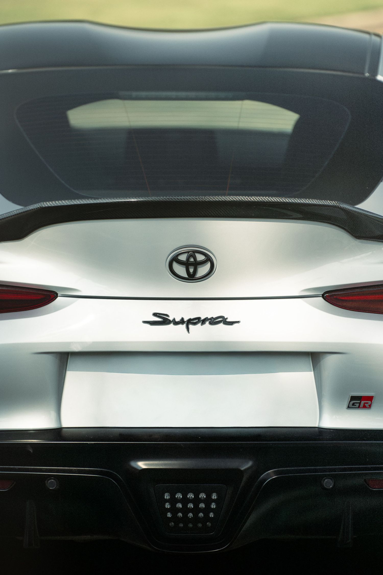Close-up view of Toyota and Supra logos on white car exterior panels.
