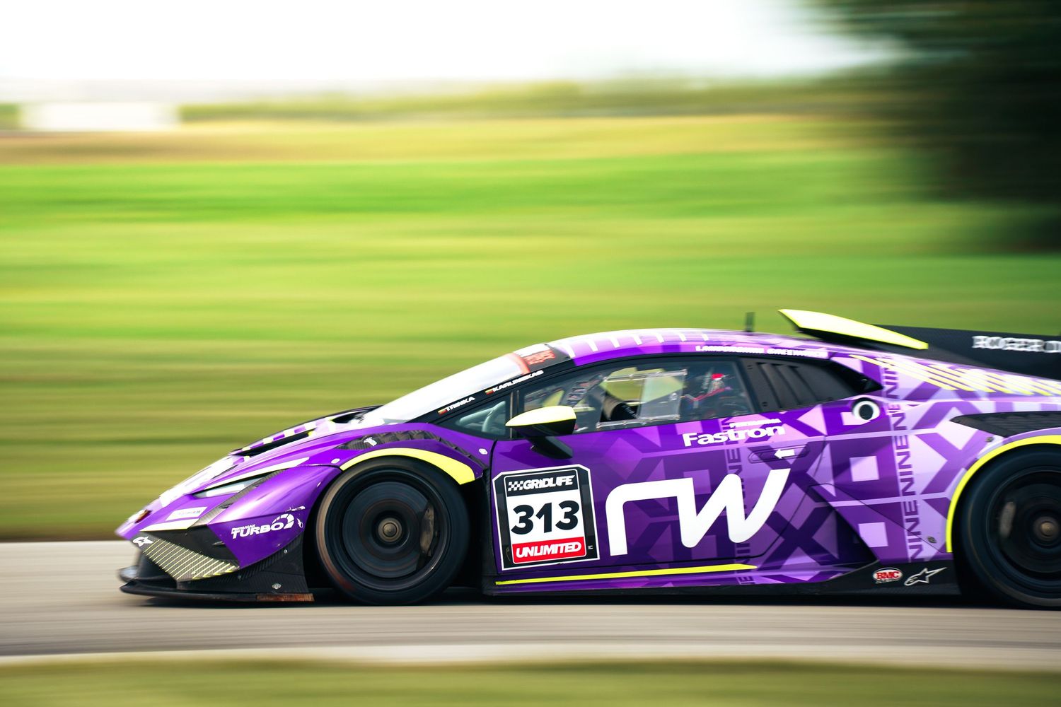 A purple Formula 1 racing car speeds along a racetrack with motion blur effects in the background.