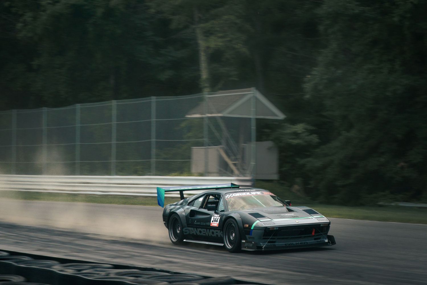 Vintage race cars competing on a professional racing circuit in moody lighting.
