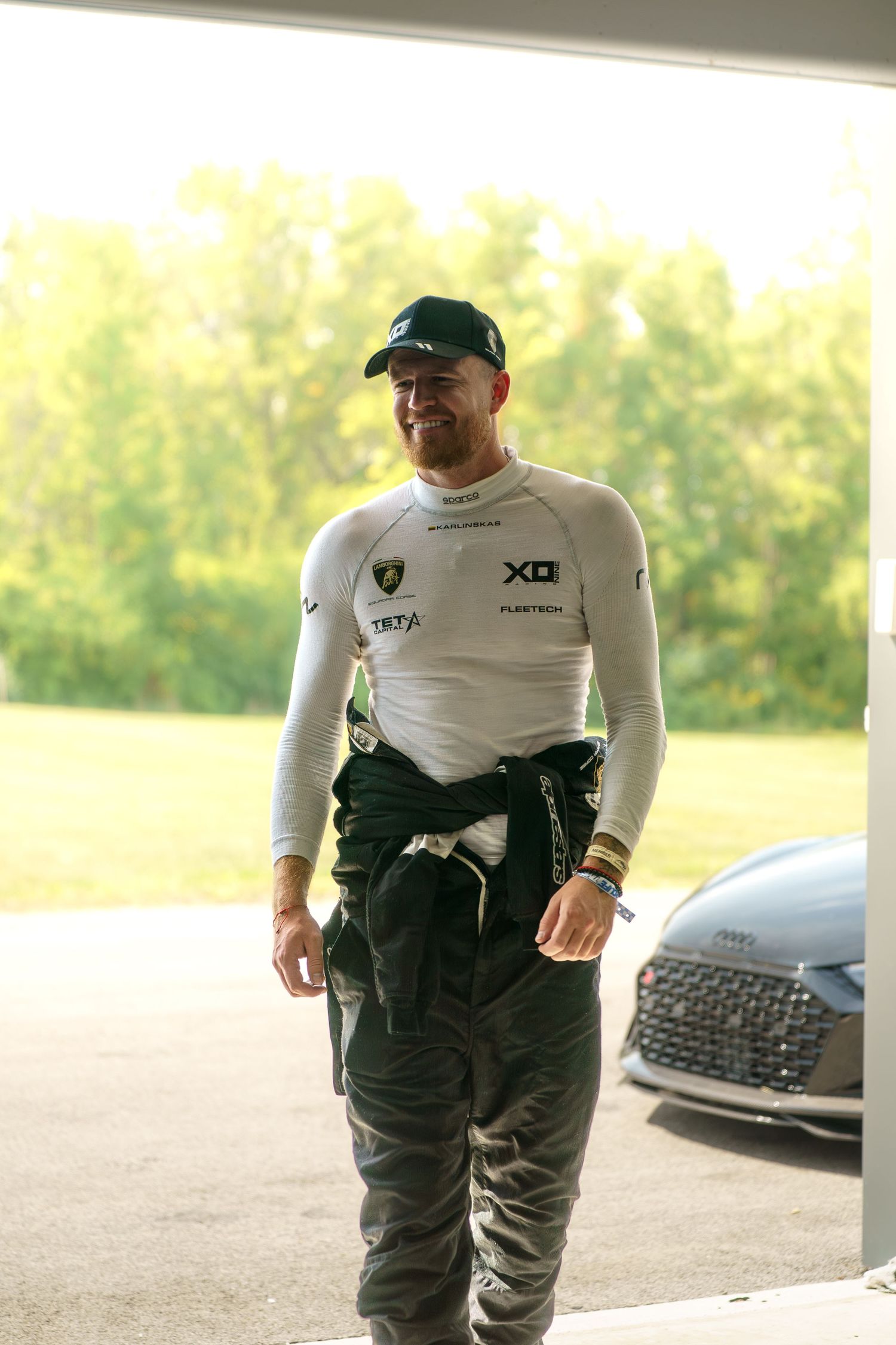 A person wearing a white long sleeve shirt and dark tactical pants stands outdoors in natural lighting.