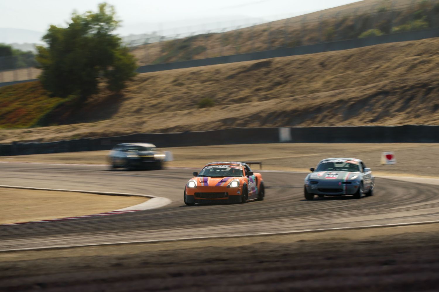 Two sports cars race along a winding mountain road during a competitive track event at high speed.