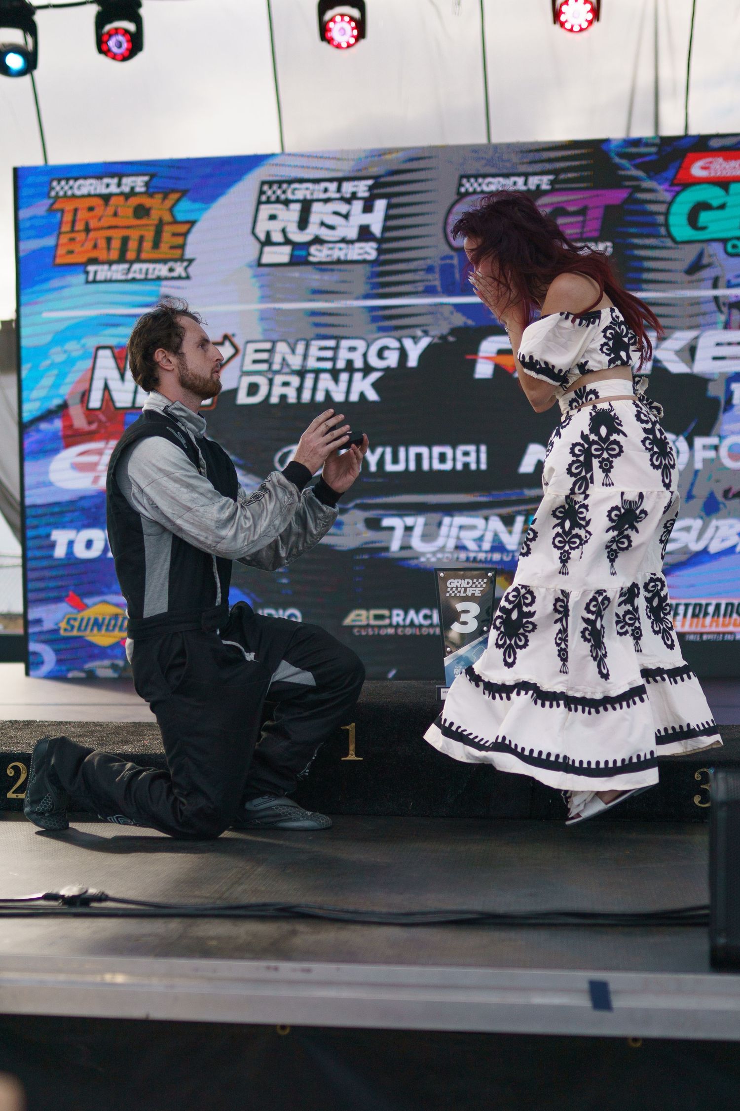 A sequence of poses showing a figure in a black and white patterned sweater sitting against a backdrop with sponsor logos.