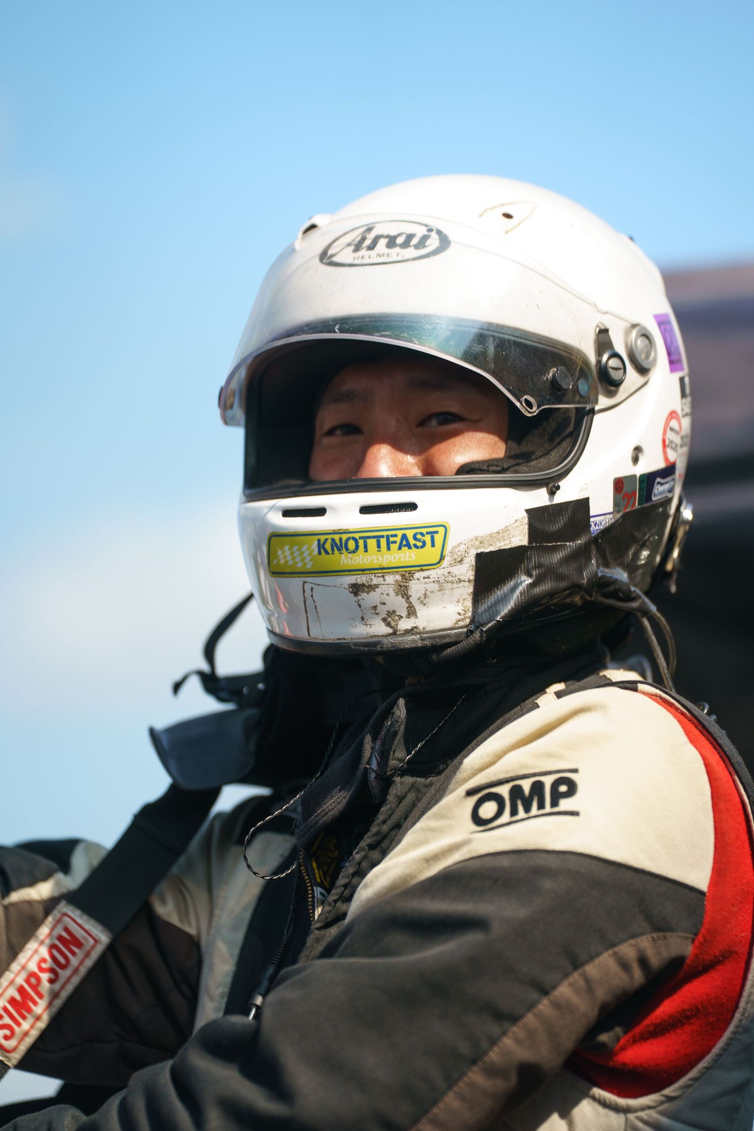 Race car drivers wearing white Arai helmets focused intently during motorsport competition.
