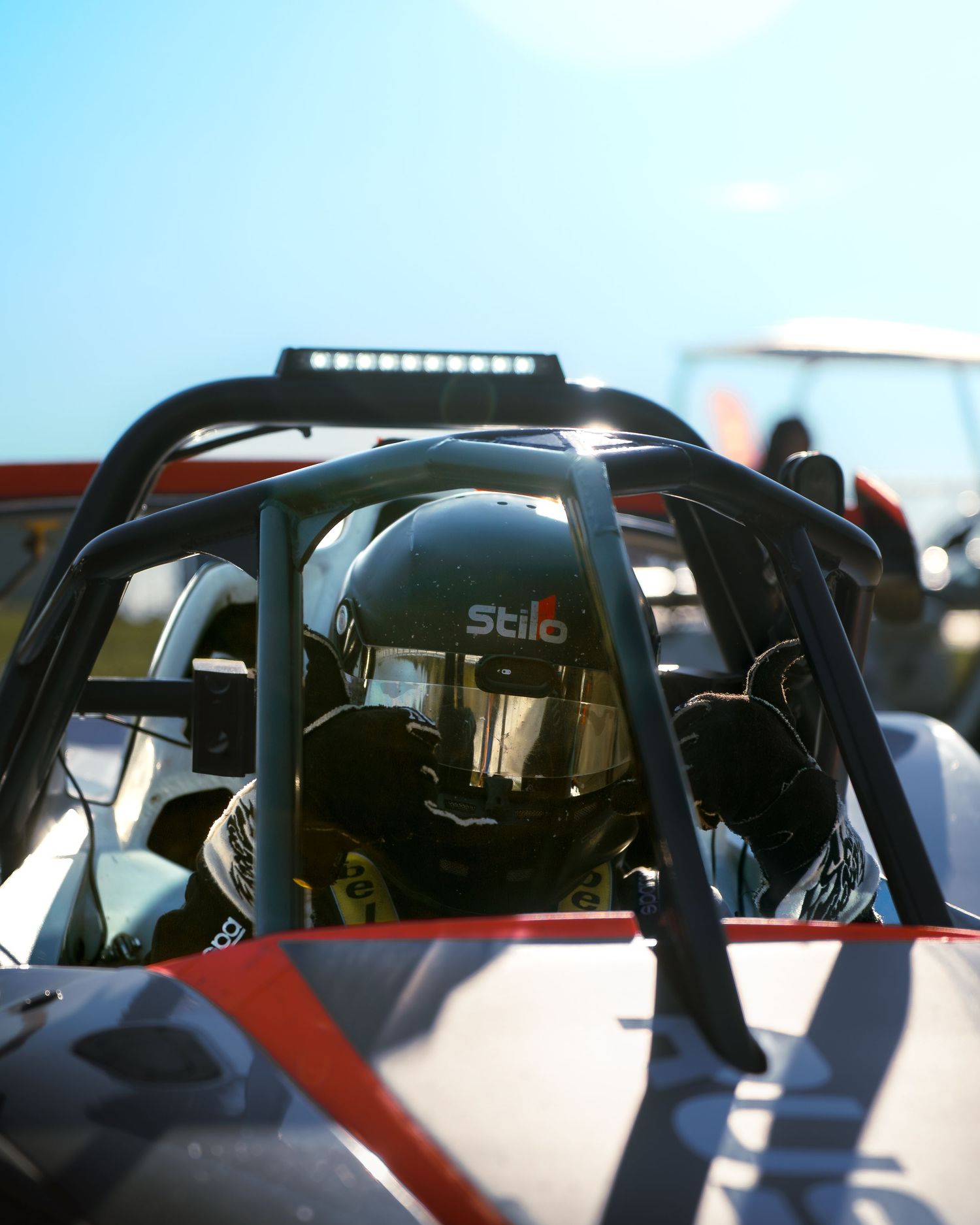 Interior view through the side window of a race car showing the driver's compartment and roll cage during a motorsport event.