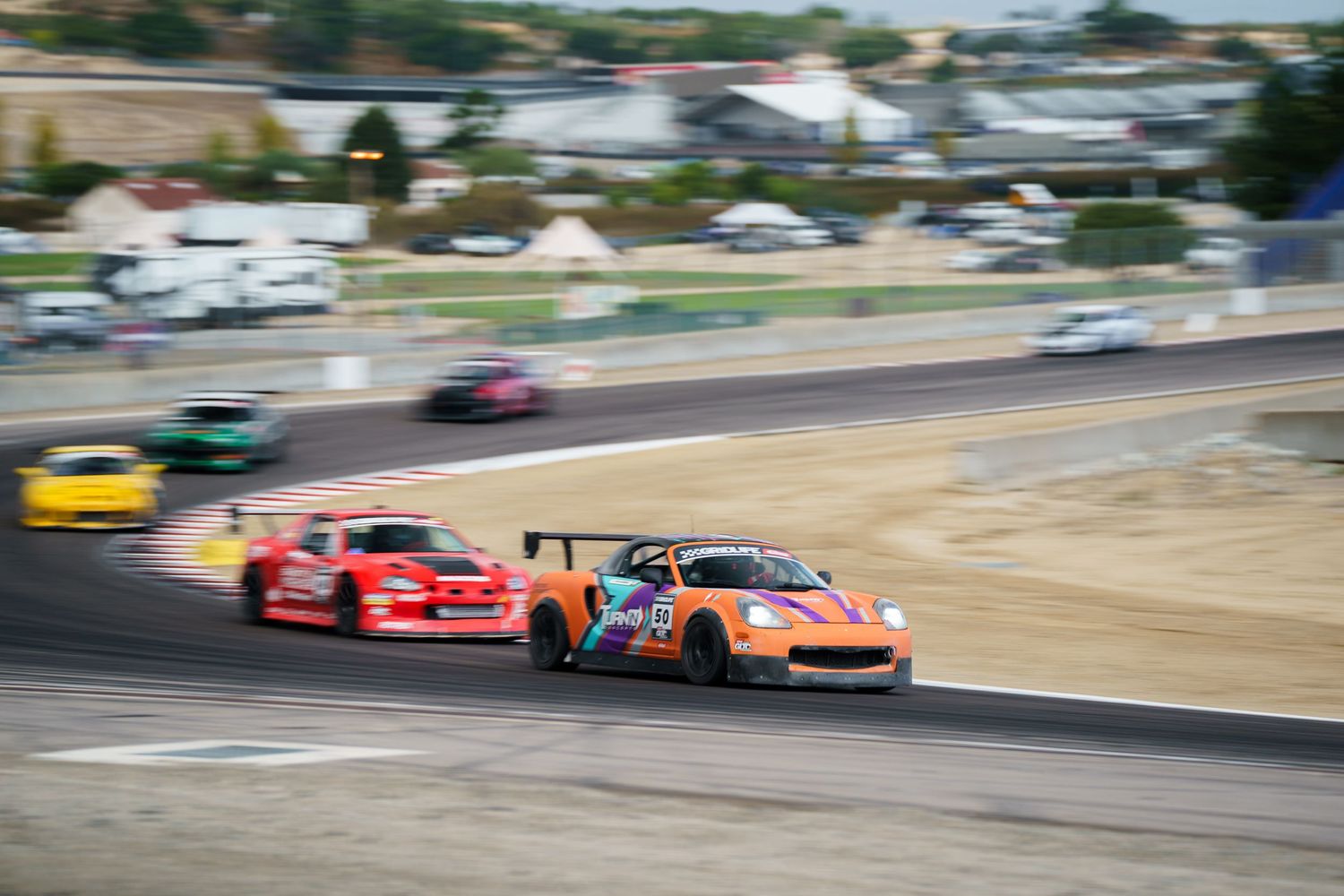 Race cars compete on a professional racing track during a motorsport competition event.