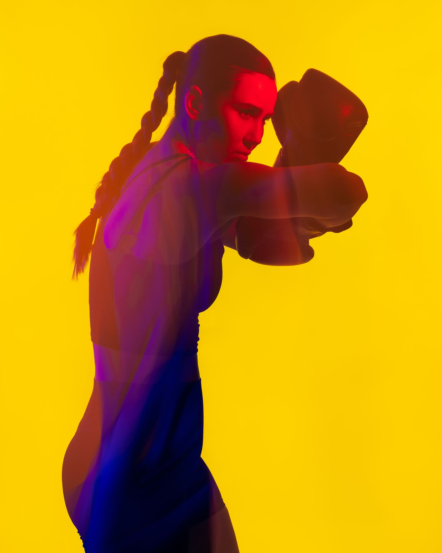 Dynamic portrait of a boxer with braids in colorful red and blue neon lighting against a yellow background.