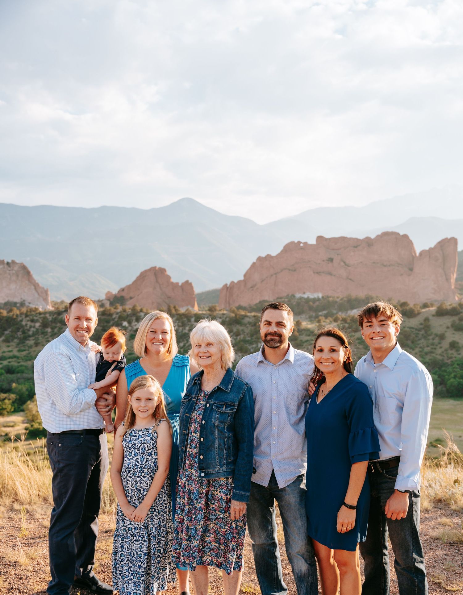 Extended family posing together outdoors with rocky mountain landscape behind them.
