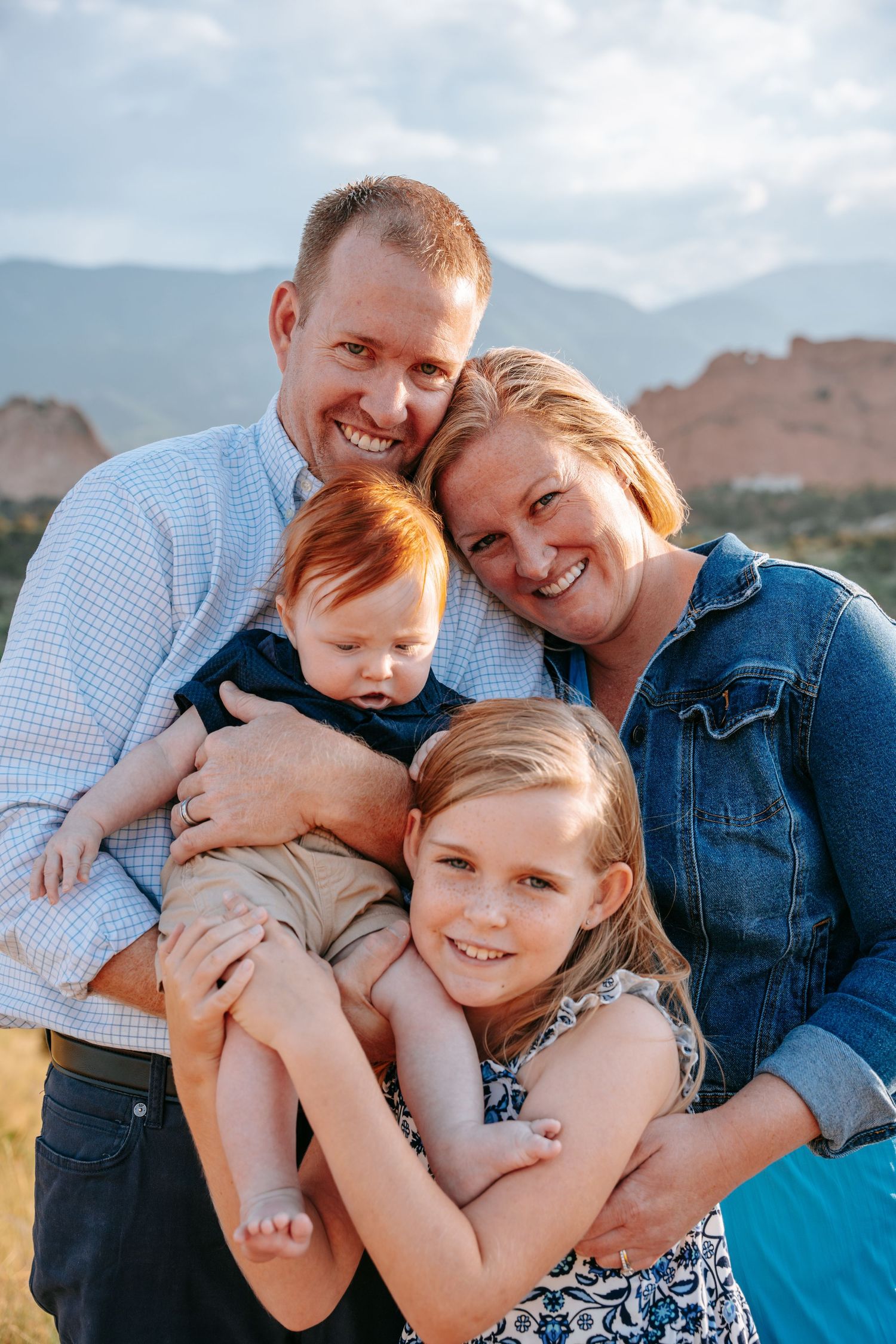 Smiling family of four with two children posing at Garden of the Gods.