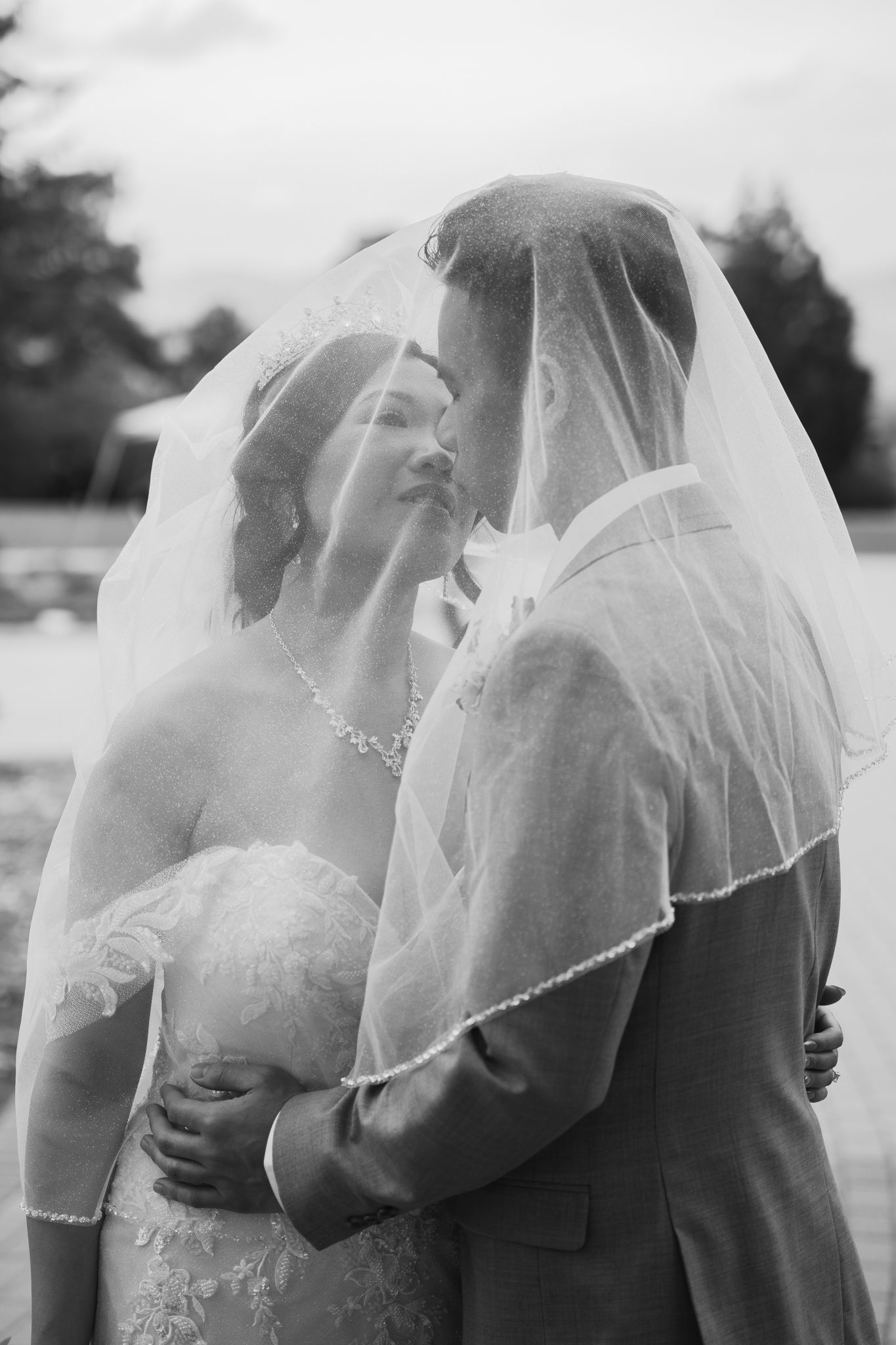 A romantic black and white photo sequence showing a bride and groom kissing under a delicate white veil in Colorado