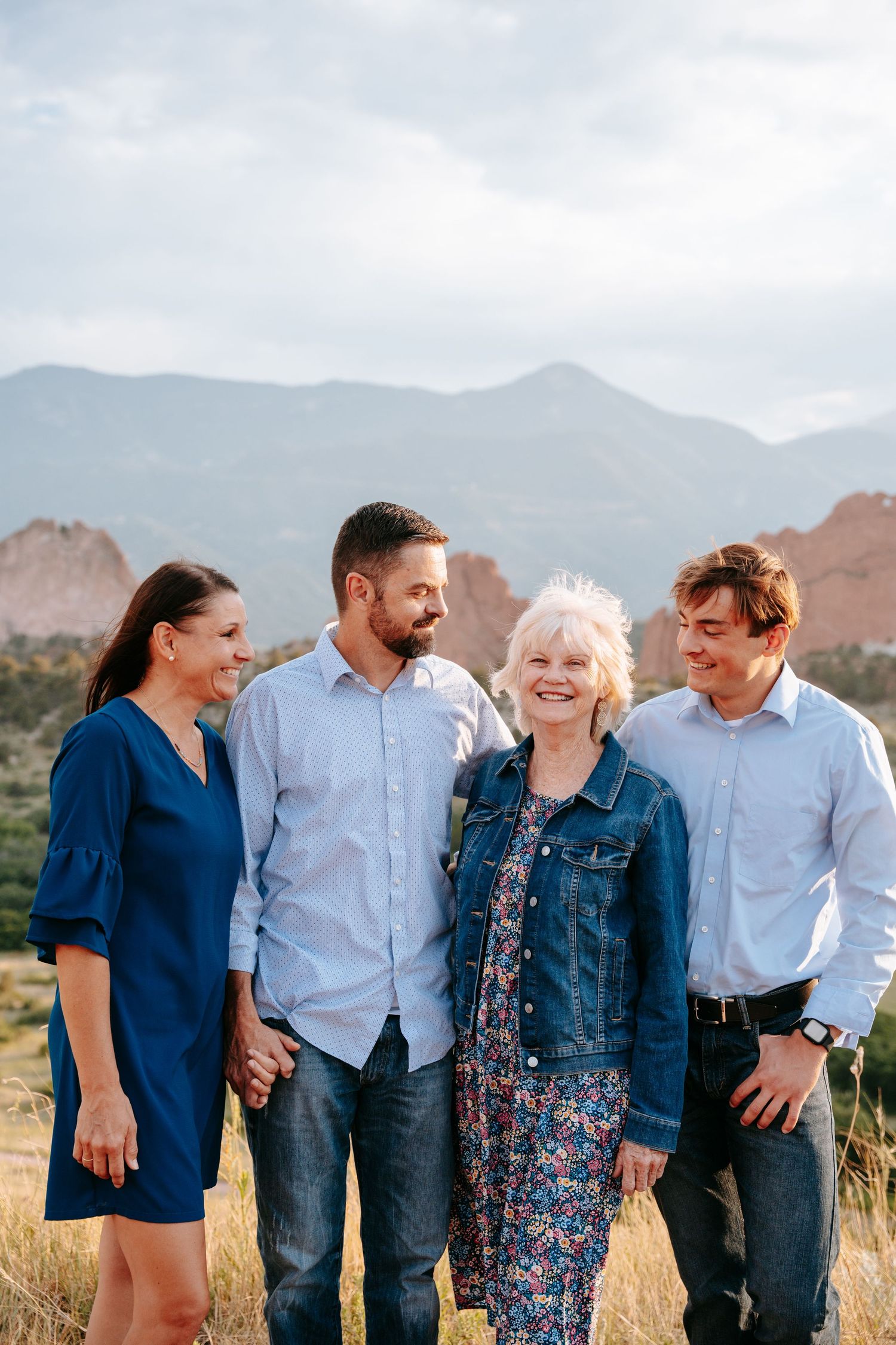 Woman, two men, and older woman laughing together in a mountain field.