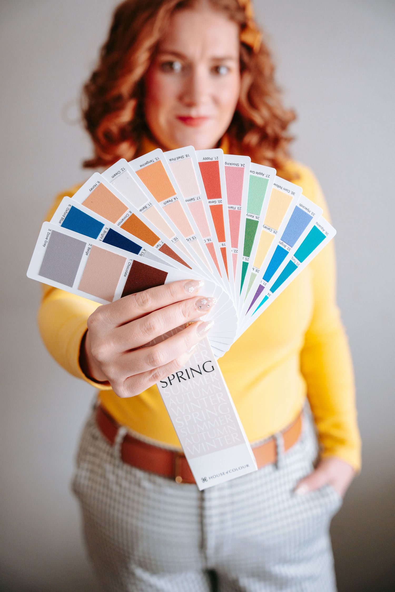 Woman holding a spring color palette fan with swatches in various colors for seasonal color analysis.