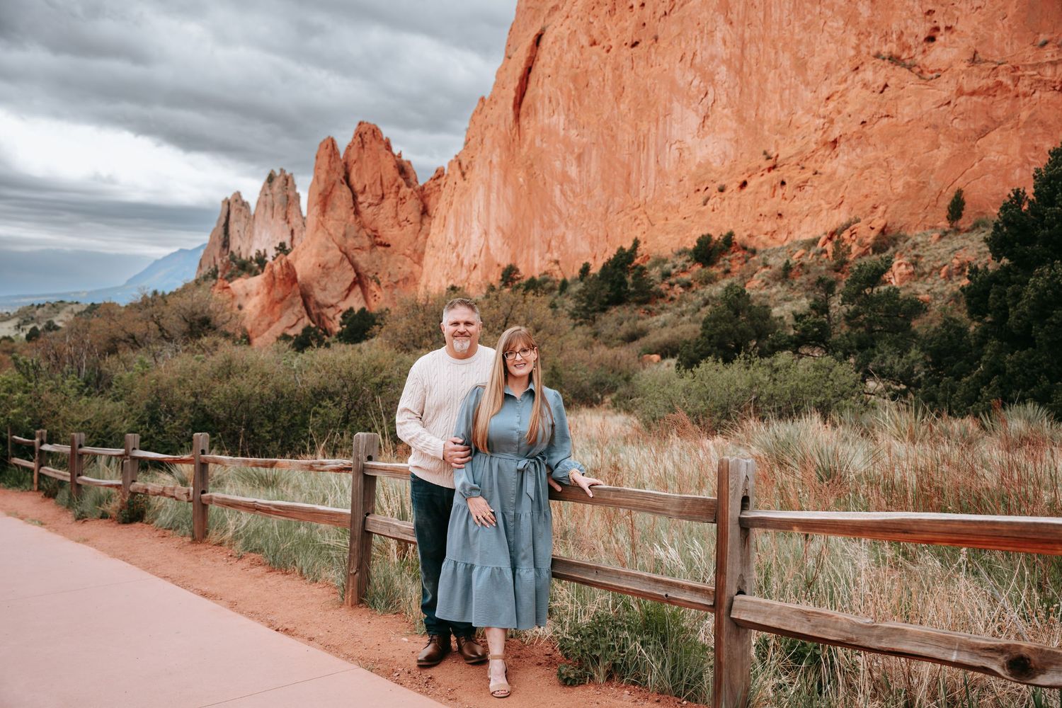 Couple smiling together at Garden of the Gods with red rock formations in the background.