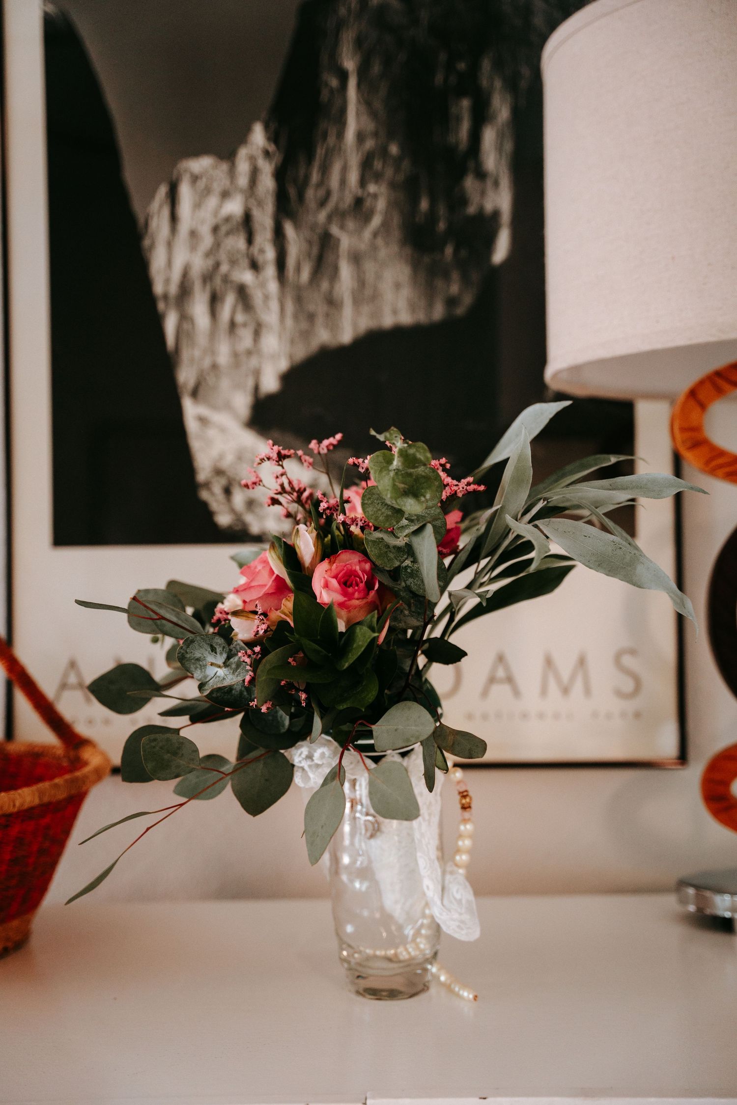 Pink roses and eucalyptus wedding bouquet in glass vase before Ansel Adams black and white print.