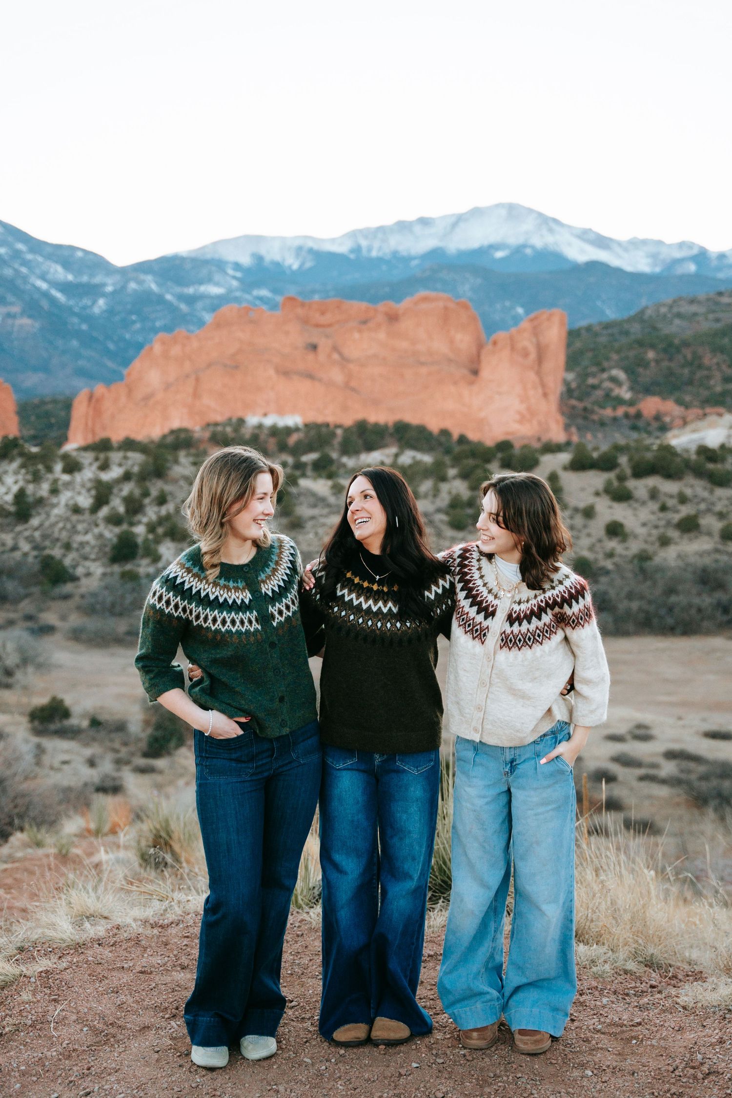 Three women in Nordic sweaters laughing at Garden of the Gods, Colorado.