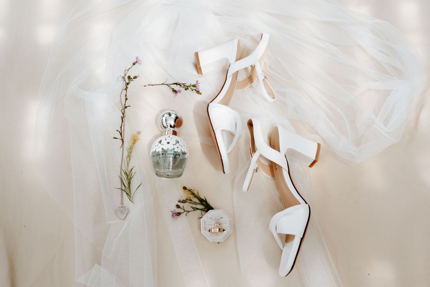 White strappy block-heel bridal sandals styled with a vintage perfume bottle, dried wildflowers and a ring on soft tulle.