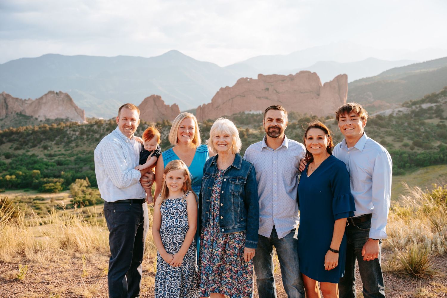 Multi-generational family smiling together with scenic red rock formations in background.