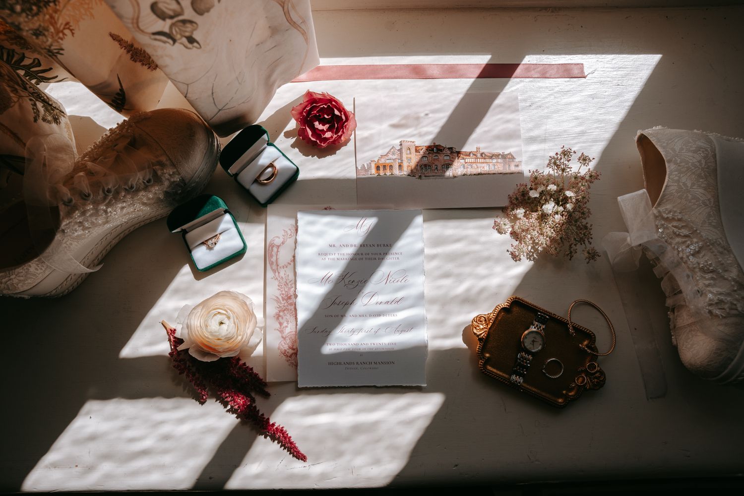 Flat lay of wedding details including rings, bouquet, shoes, and accessories arranged on a windowsill.