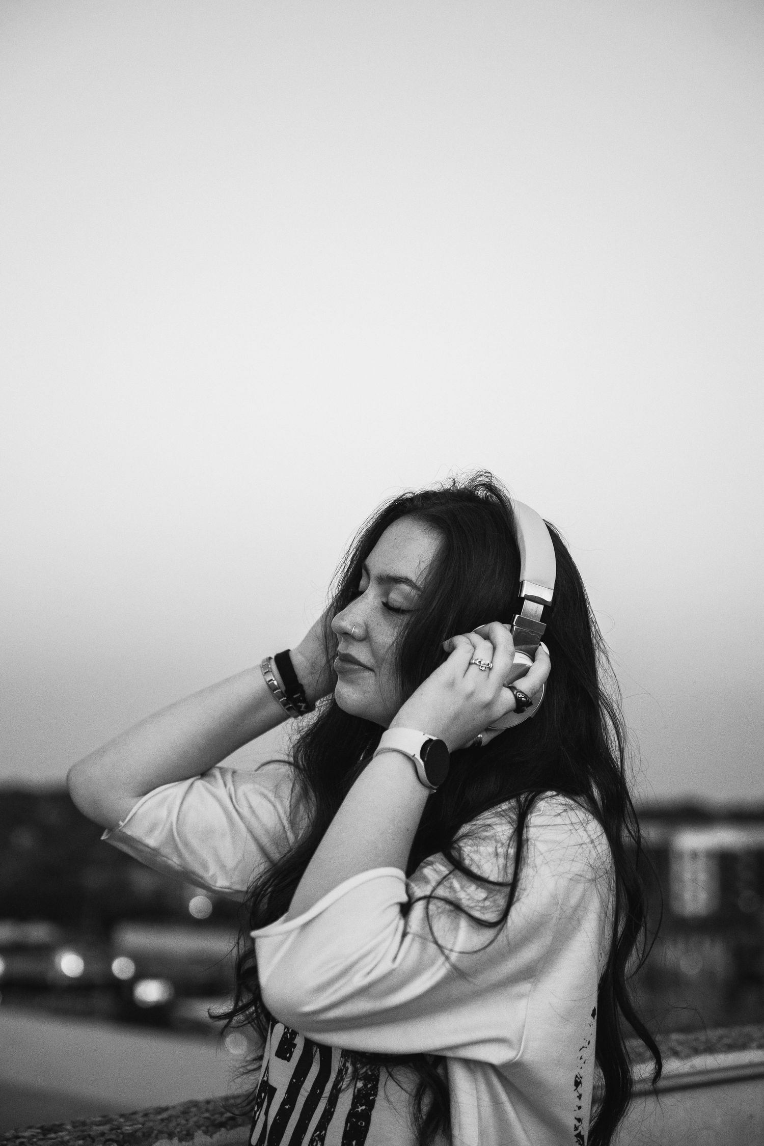Black and white portrait of woman enjoying music with headphones outdoors.
