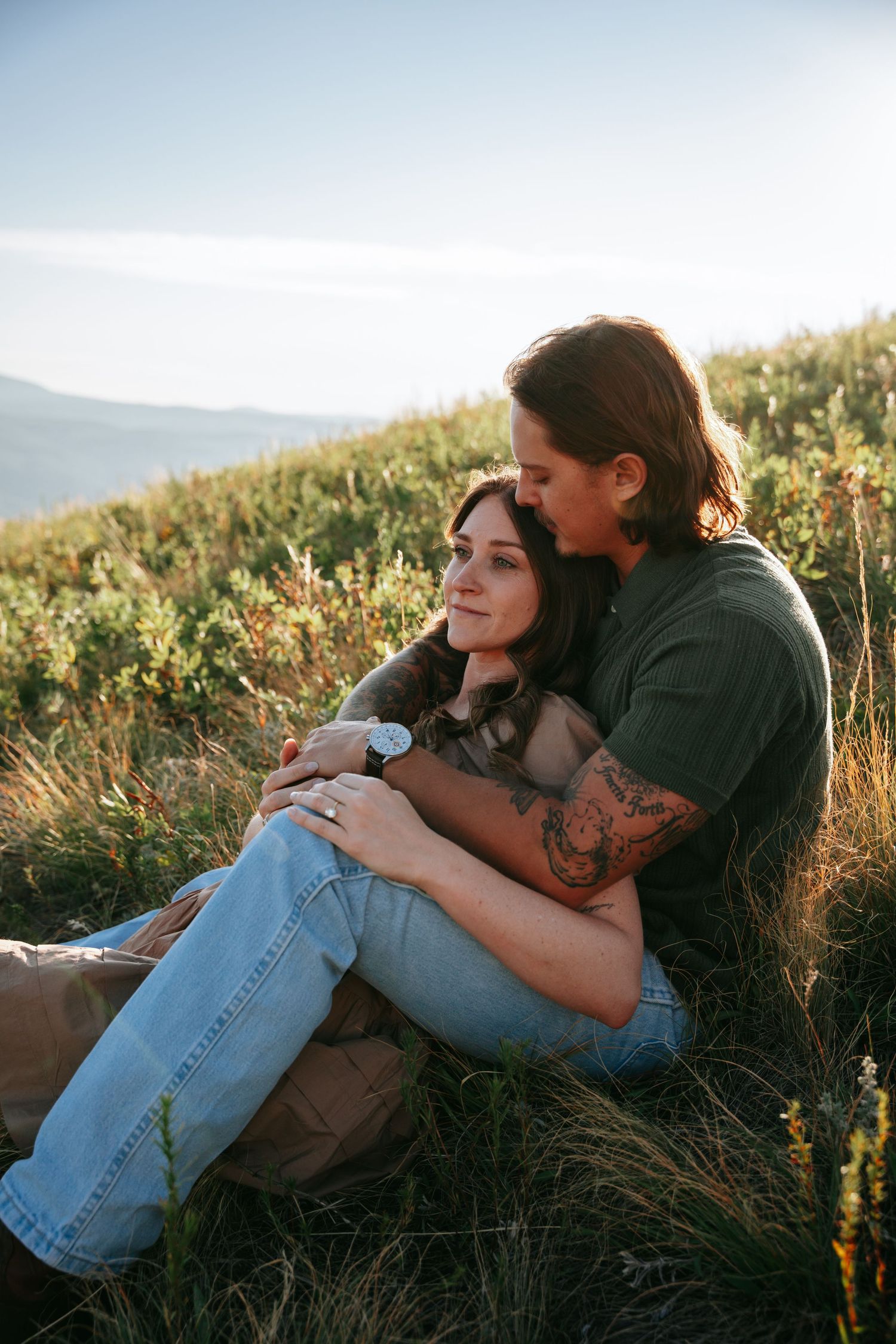 Couple looking off in the distance sitting in a meadow