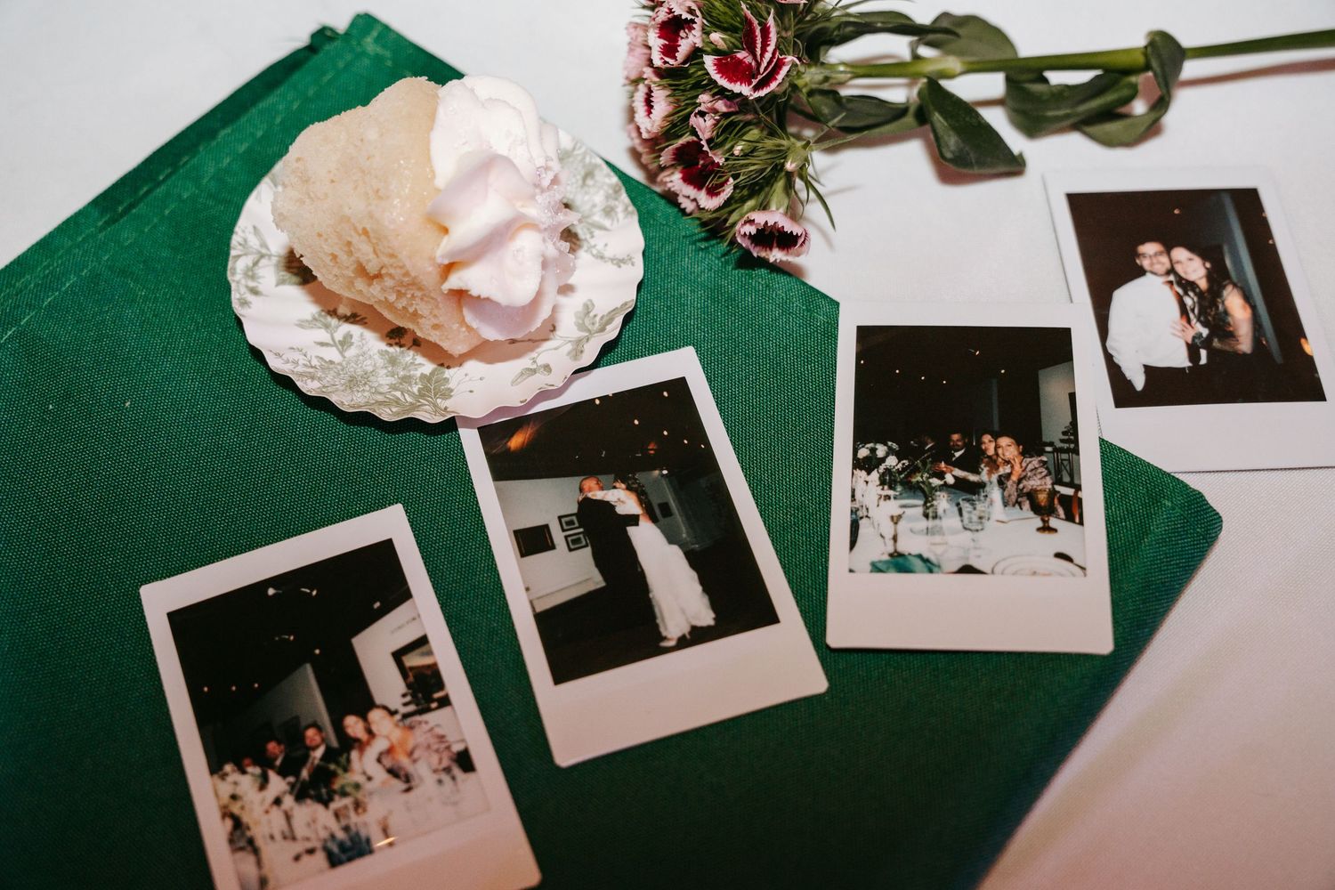 Polaroid photos and a seashell on a green velvet book at a wedding reception.
