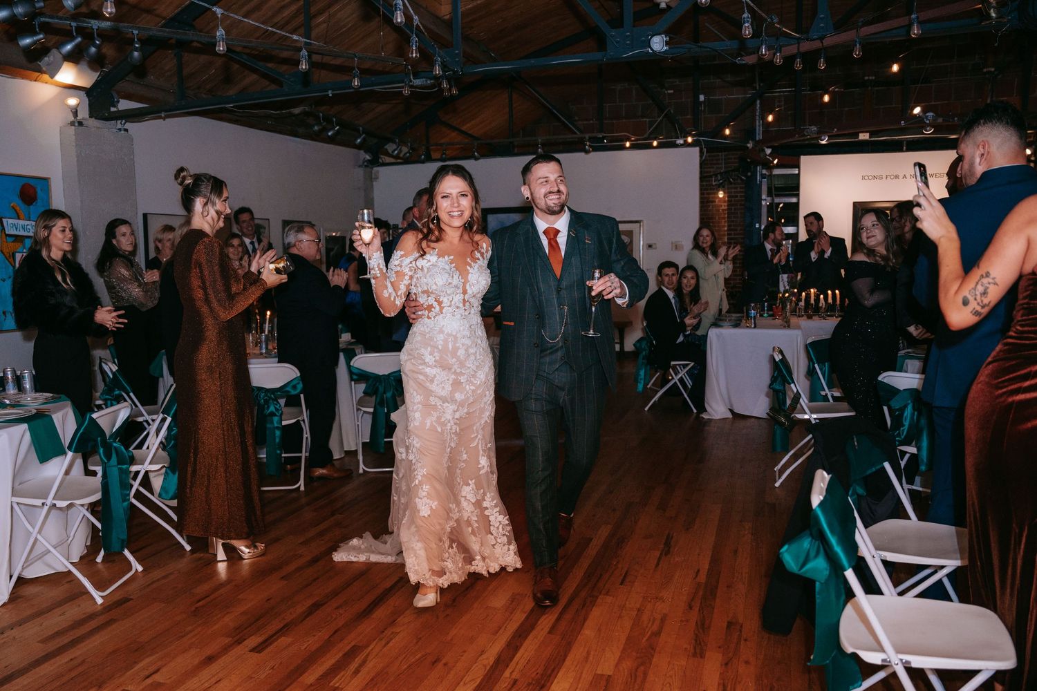 Bride and groom make a grand entrance holding champagne flutes at their wedding reception.