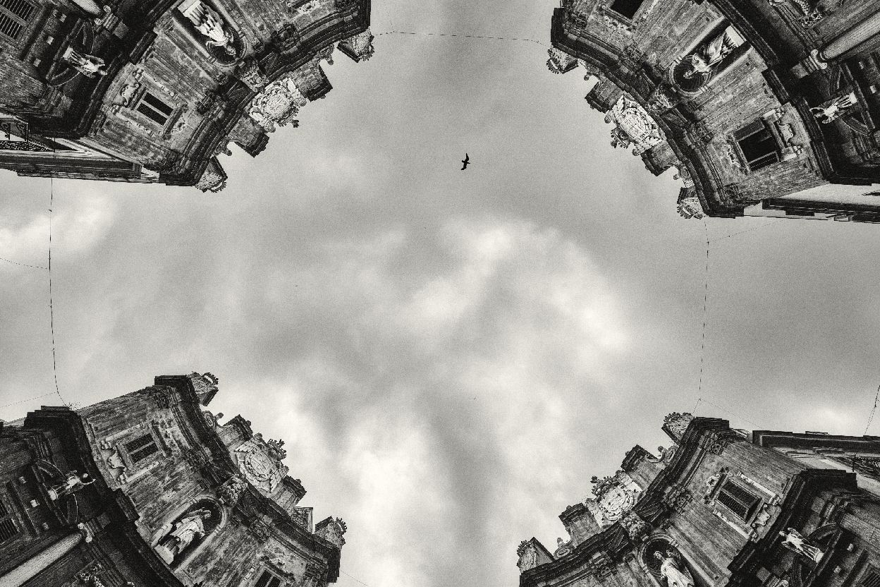 Black and white panoramic cityscape of historic buildings with dramatic cloudy sky overhead.